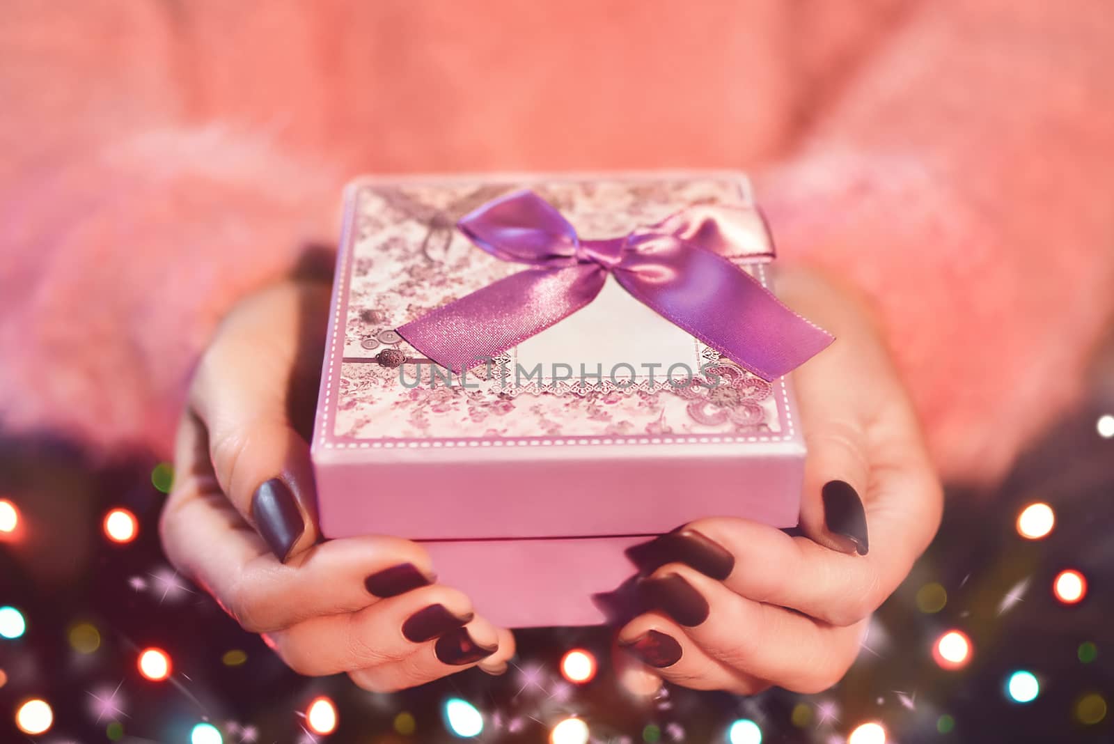 Female hand holding a pink gift box. The Valentines day and Christmas theme