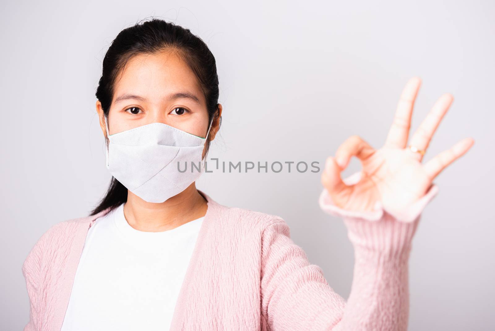 Asian beautiful woman wearing surgical protection face mask hygiene against coronavirus her show OK sign, studio shot isolated on white background with copy space, COVID-19 or corona virus concept