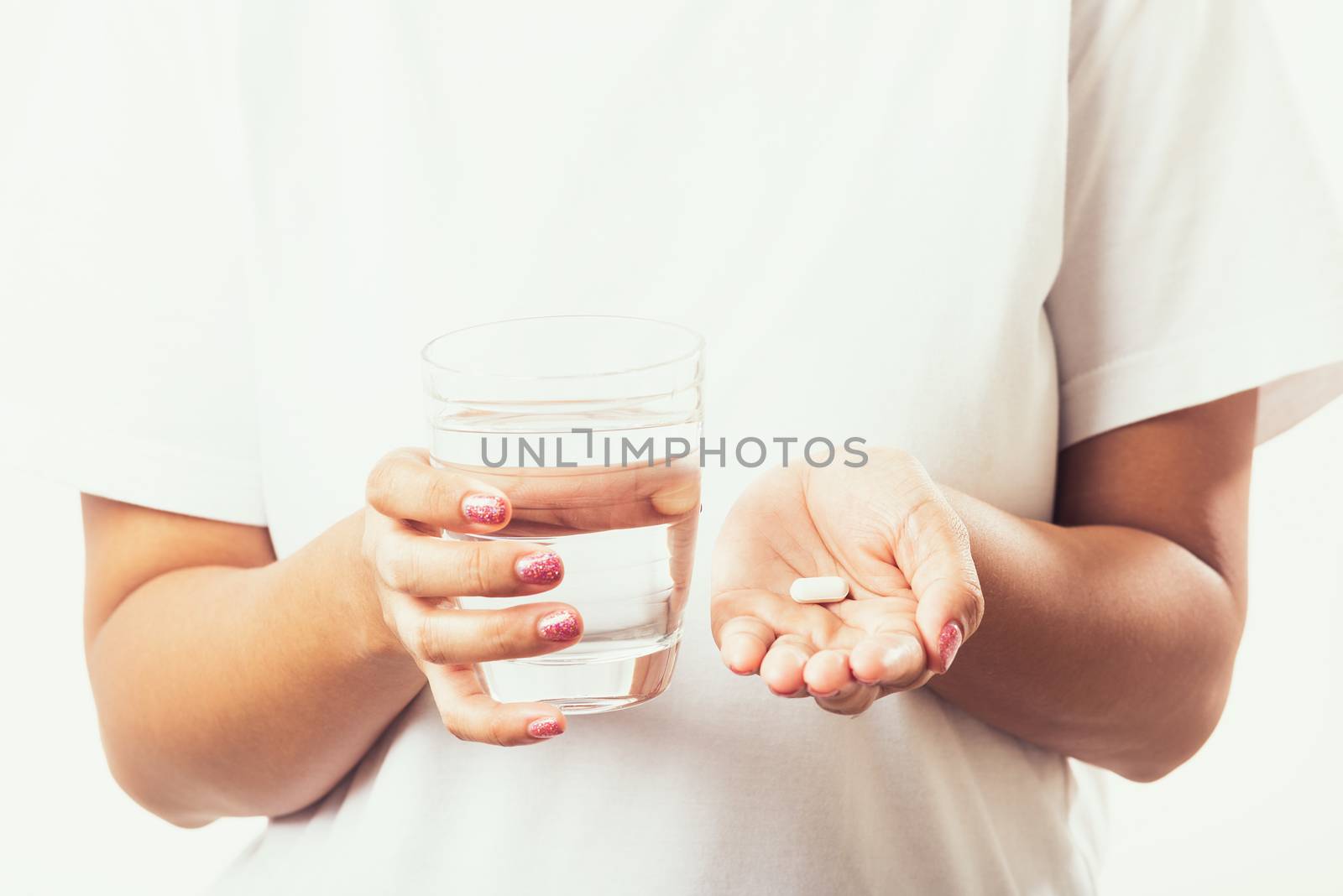 Closeup young Asian woman hold pill drugs in hand ready take medicines with a glass of water, studio shot isolated on white background, Healthcare and medical pharmacy concept