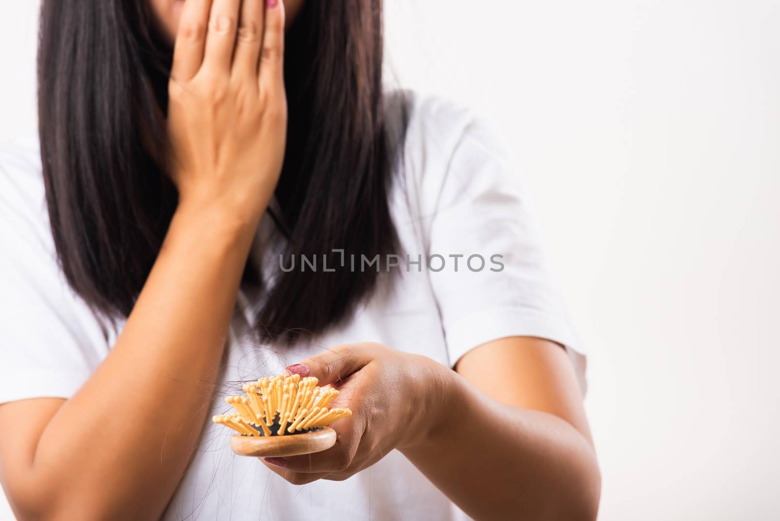 Asian woman unhappy weak hair problem her hold hairbrush with damaged long loss hair in the comb brush on hand and she shocked use hand cover mouth, isolated on white background, Medicine health care