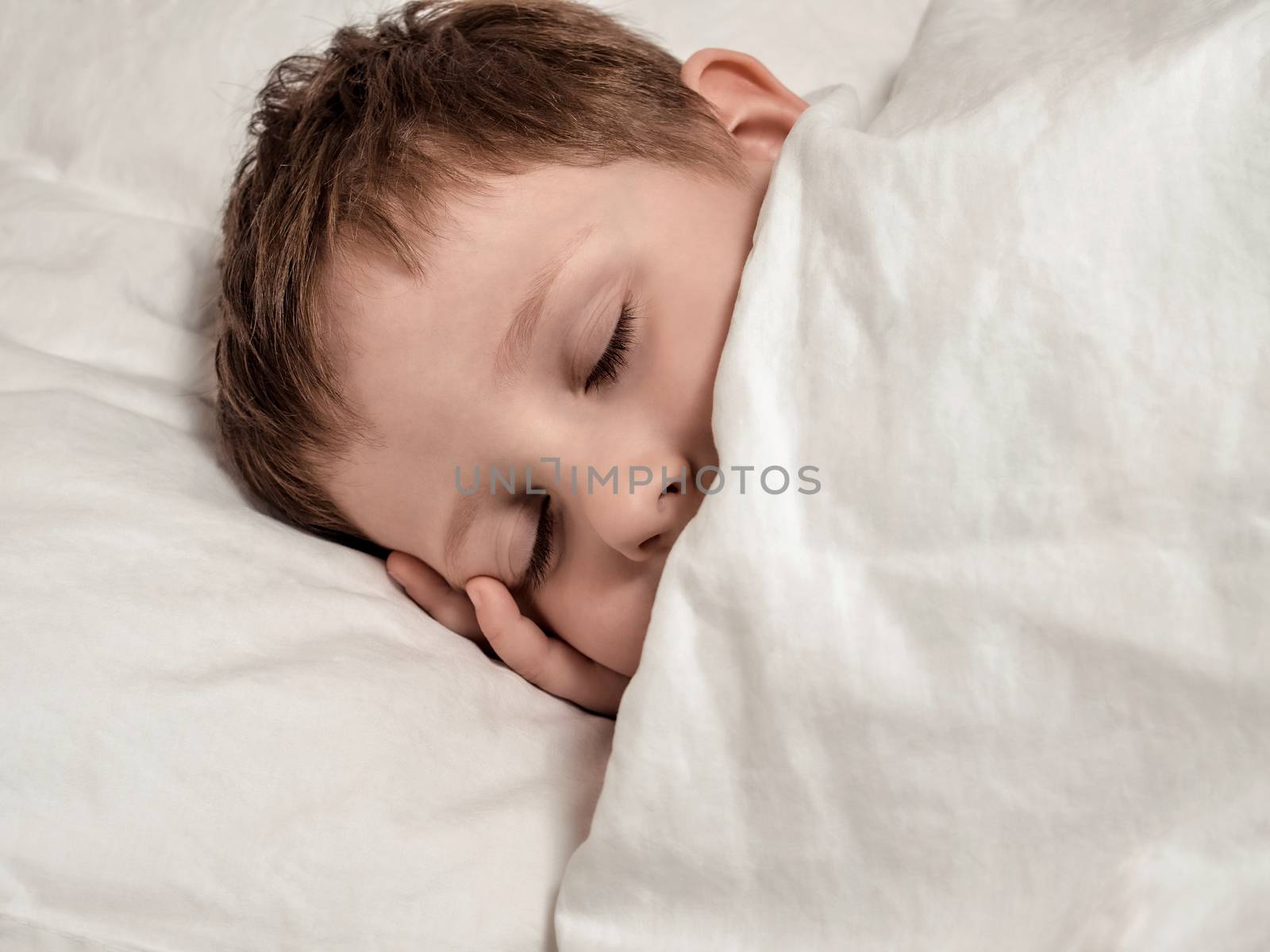 Sleeping young boy in white bed by fascinadora