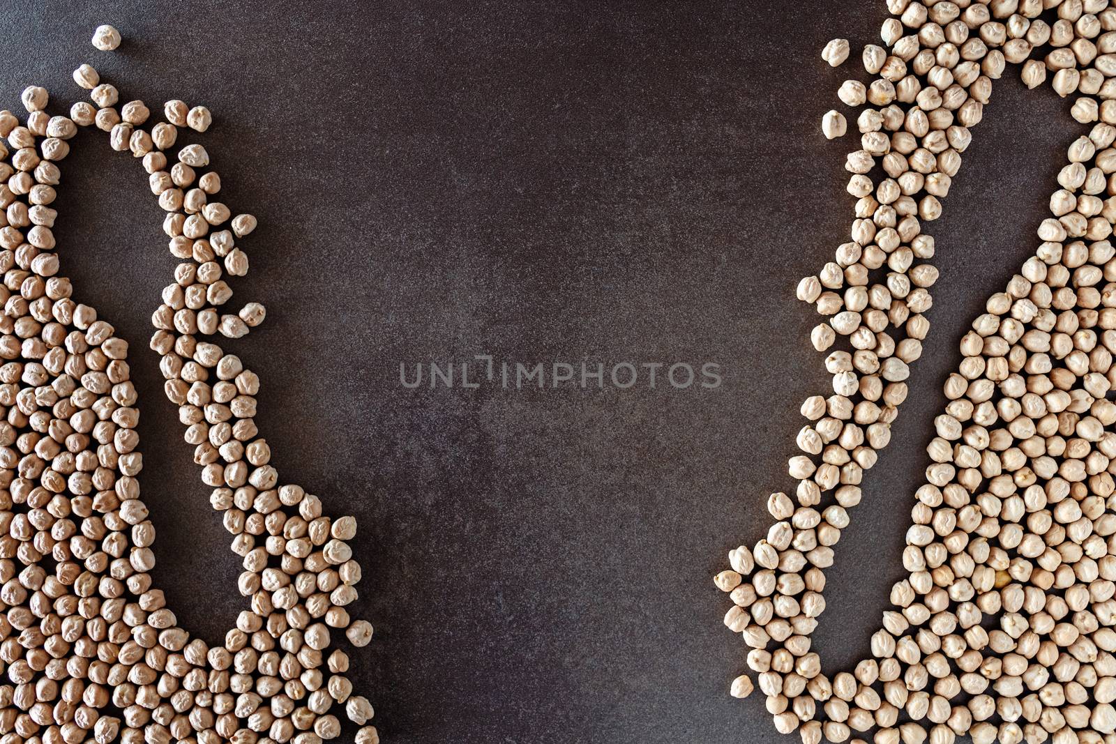 Composition of natural chickpeas with kitchen utensils, spoon and wooden fork on rustic textured bottom. View from above with space to write