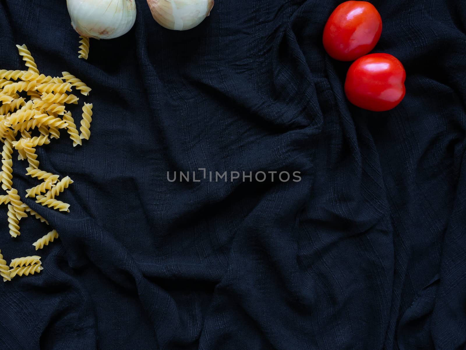 Dried Fusilli,Tomato,Black fabric background,Use as wallpaper by Kulpreya