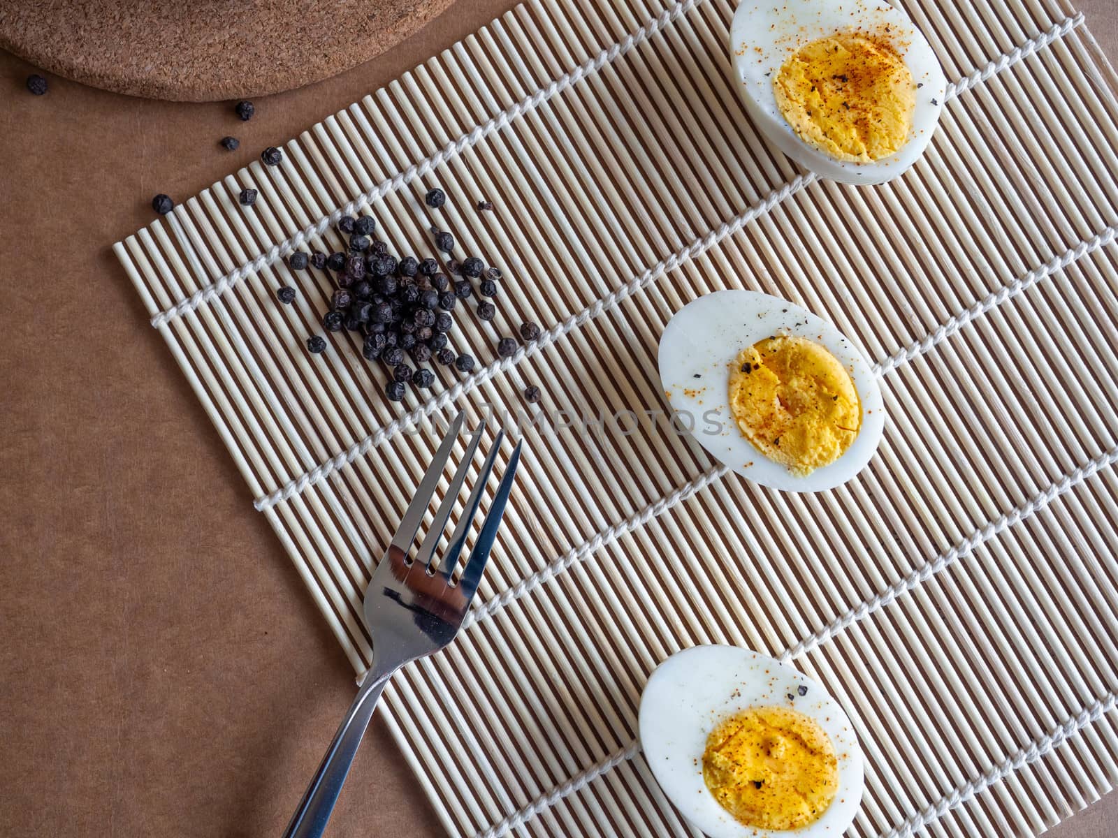 ฺBoiled egg topped with Cayenne pepper Pepper and Salt on a white dish,Egg colors white and yellow,Eat with bread