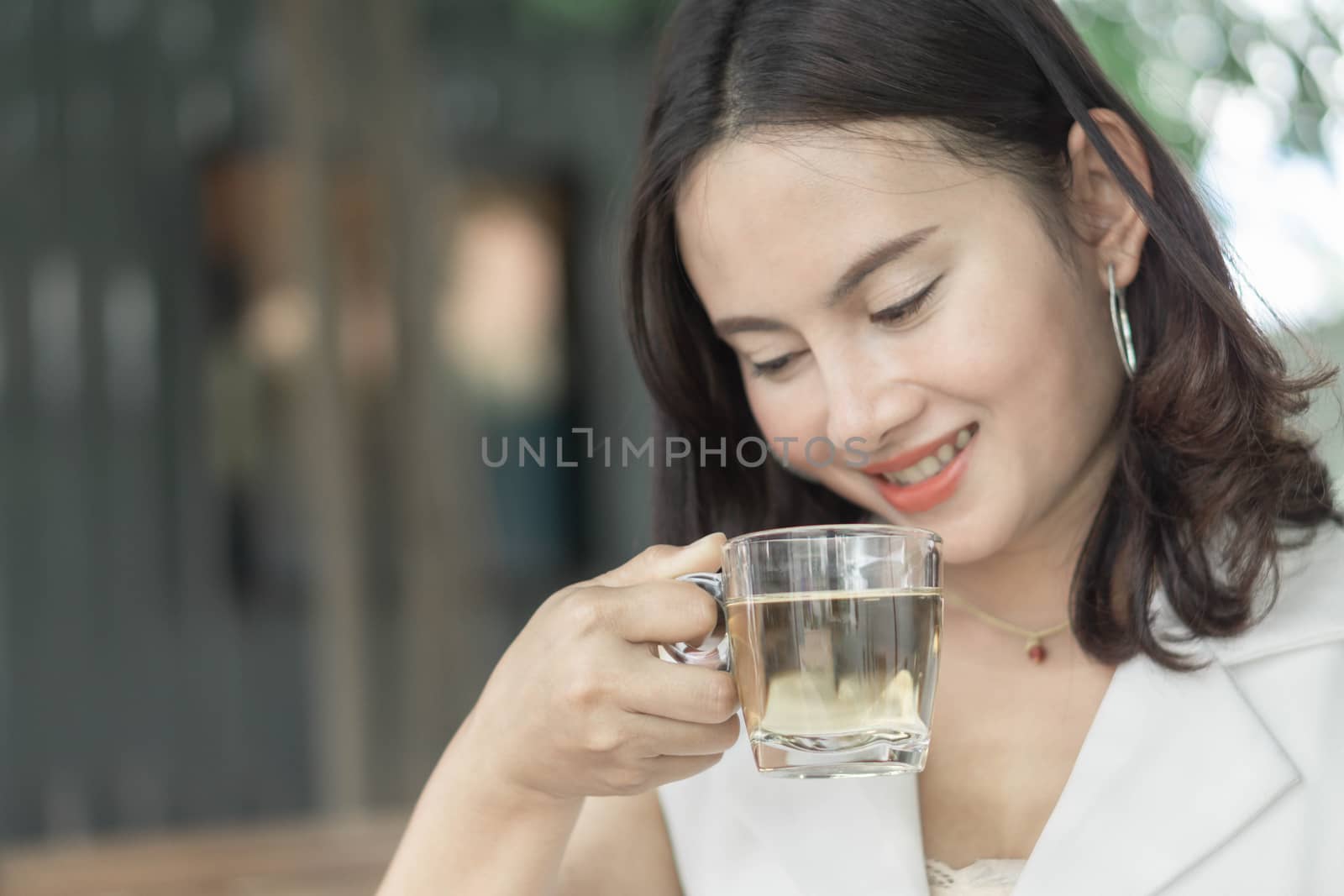 Close up woman drinking tea from glass with light in the morning, Selective focus