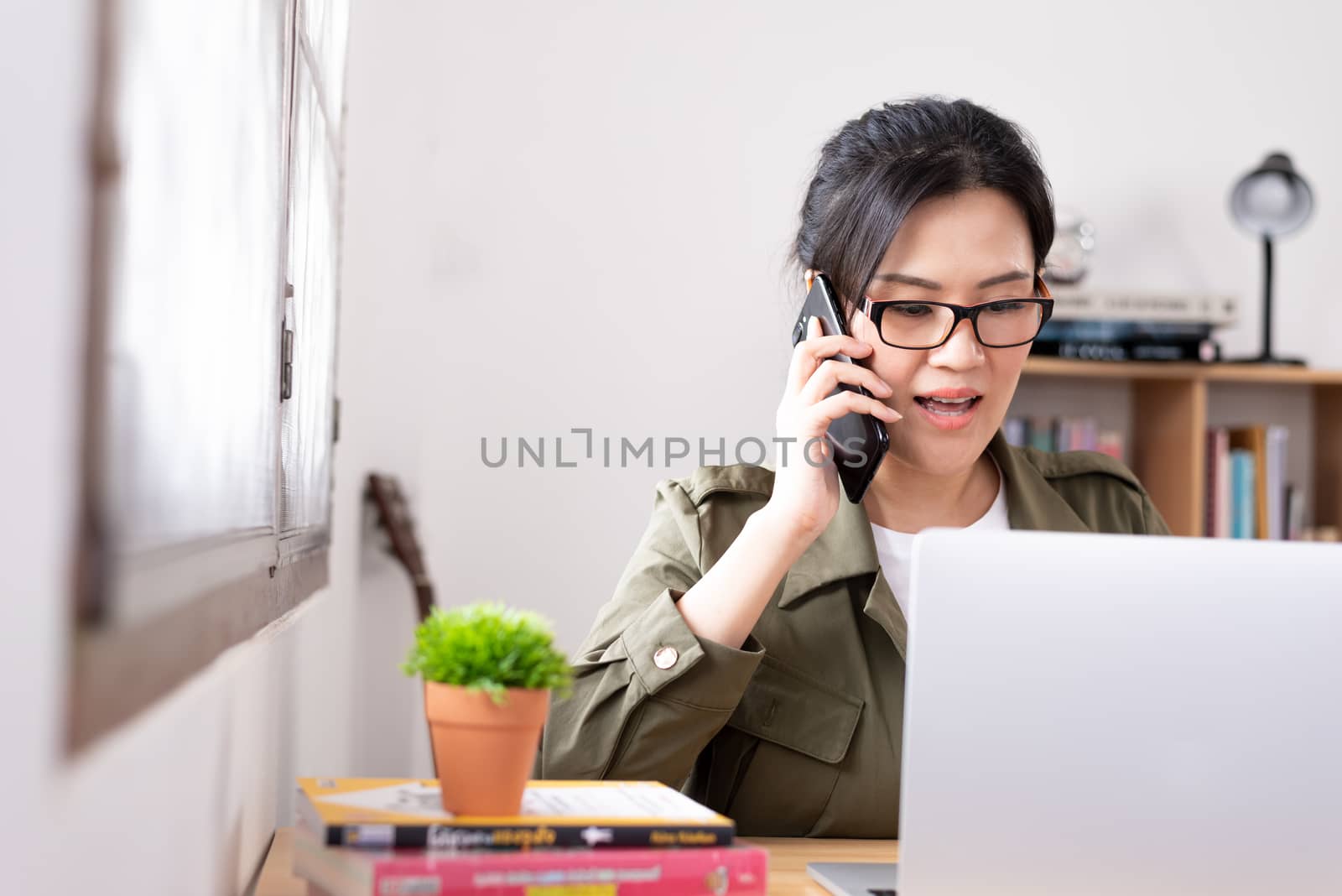 Modern young Asian woman working from home and talking with a pa by animagesdesign