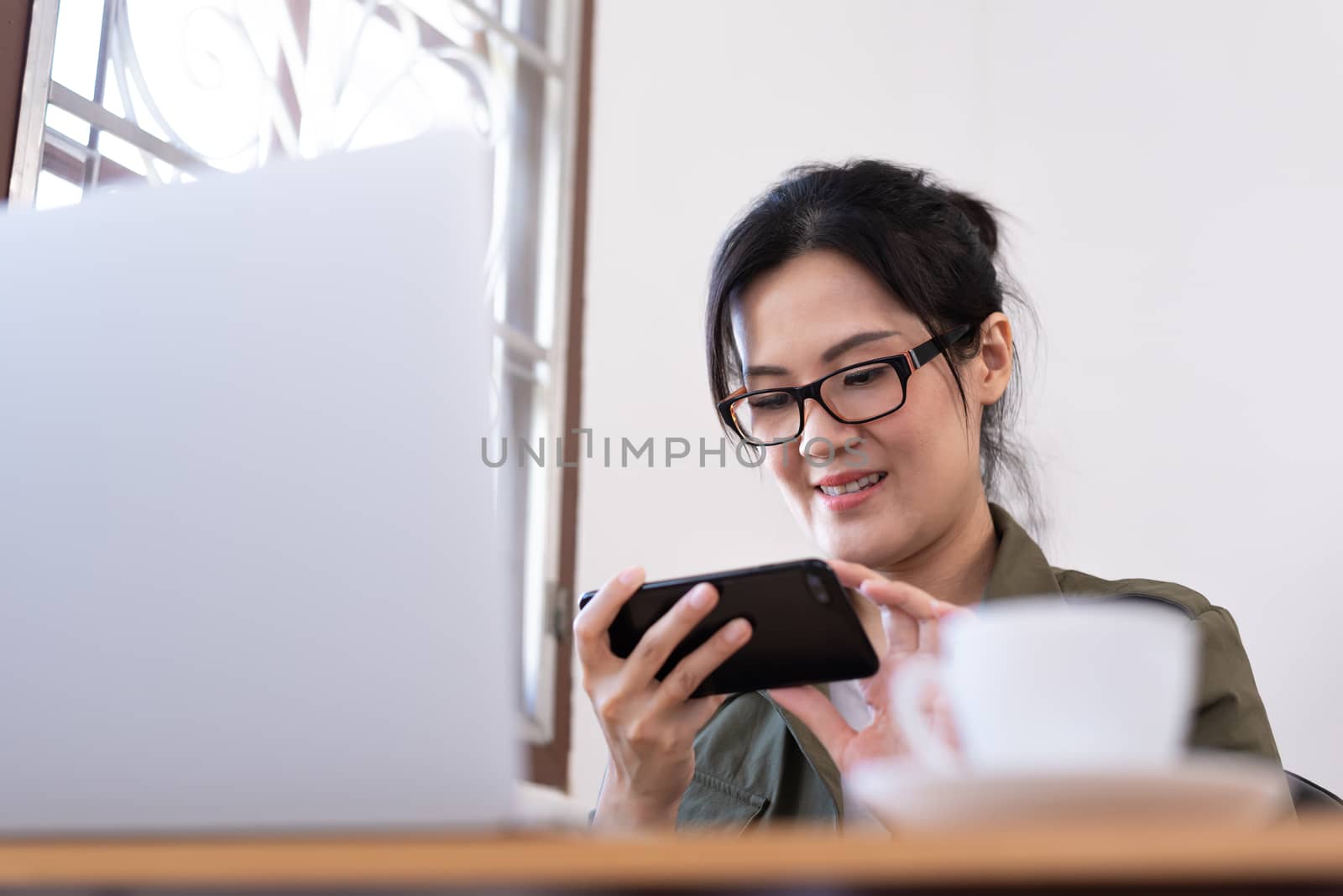 Modern young Asian woman playing a game instead of working from  by animagesdesign