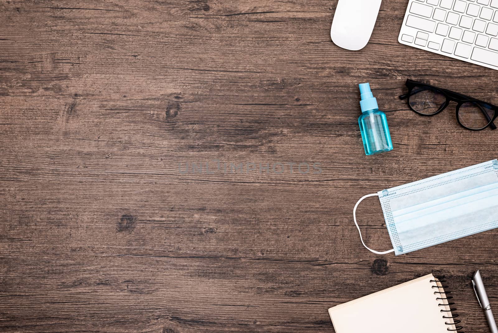 The equipment to protect COVID-19, blue mask and hand cleaner gel for preparing to work from home Isolated on wood desk.