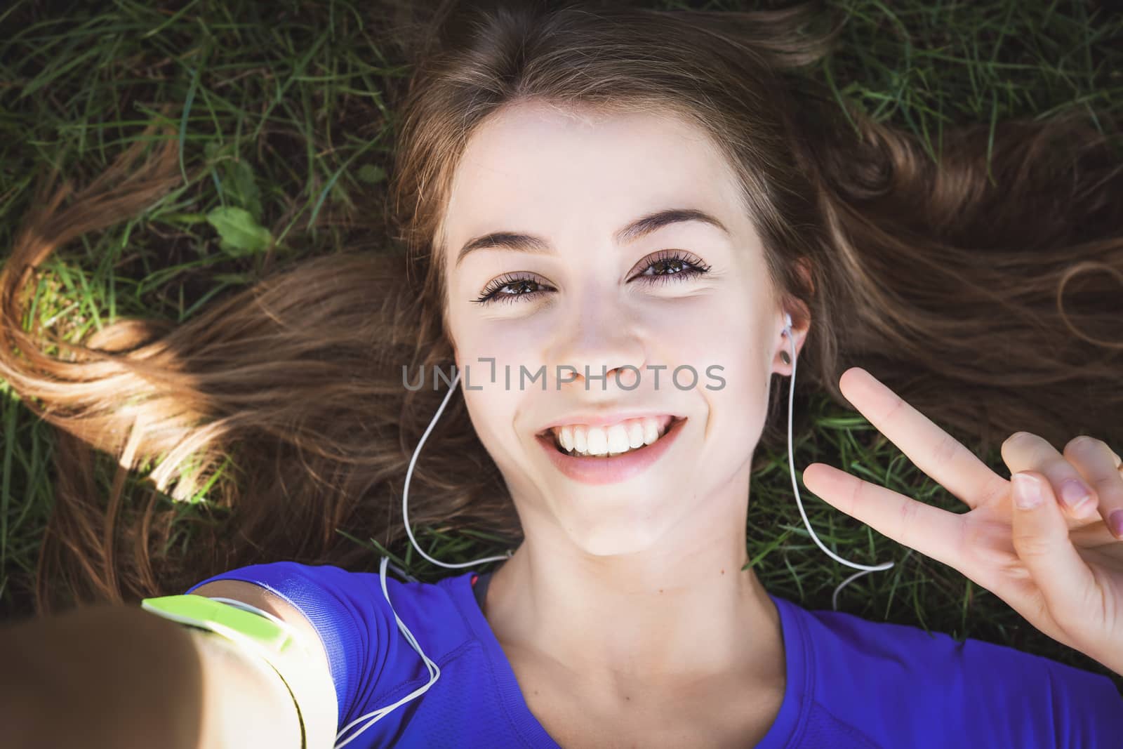 Beautiful fitness girl taking a selfie photo and showing victory gesture while resting after outdoors workout (vintage effect)