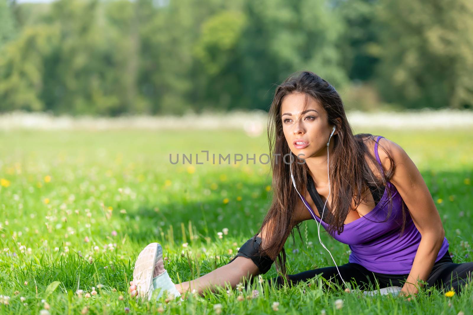 Portrait of a beautiful young girl stretching before jogging on the grass in the park on a sunny morning (copy space)