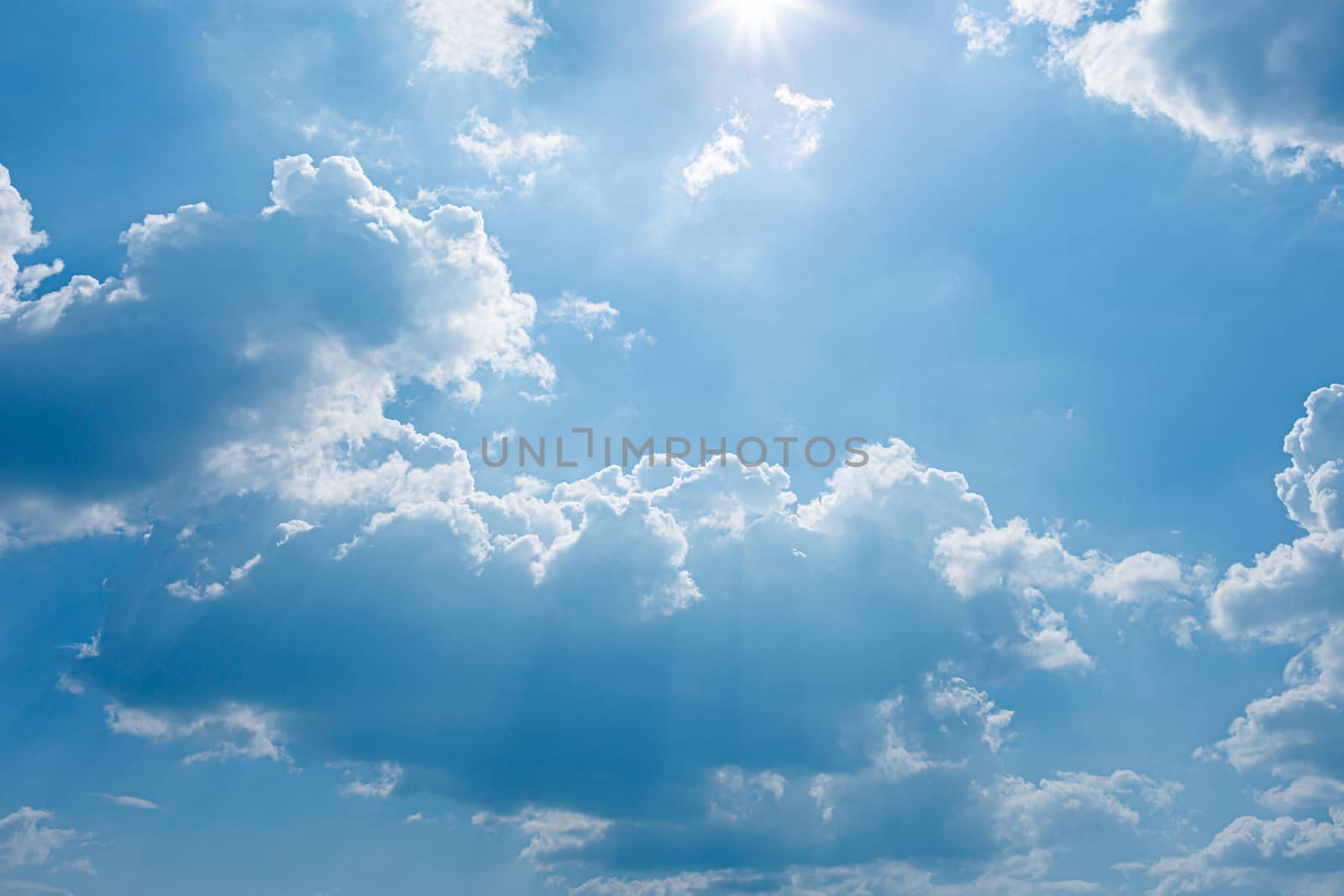blue sky and bright clouds with the sun shining by Natstocker