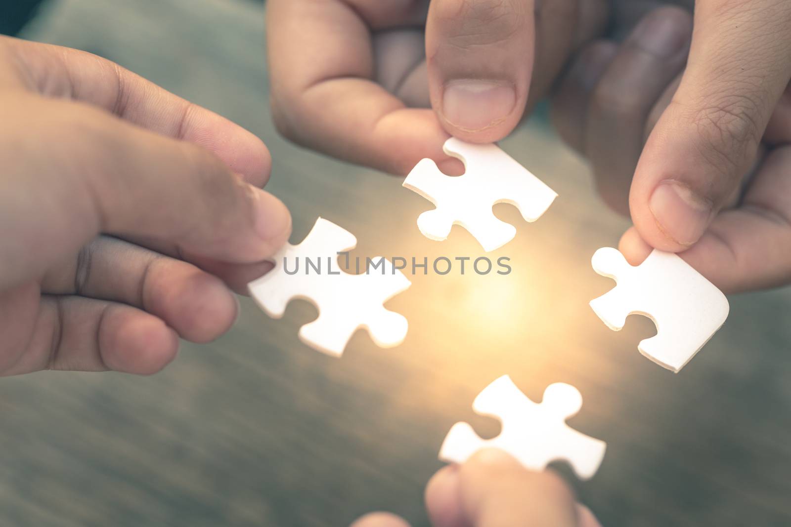 Closeup hand of diverse people connecting jigsaw puzzle which is a team work of the business detail blur