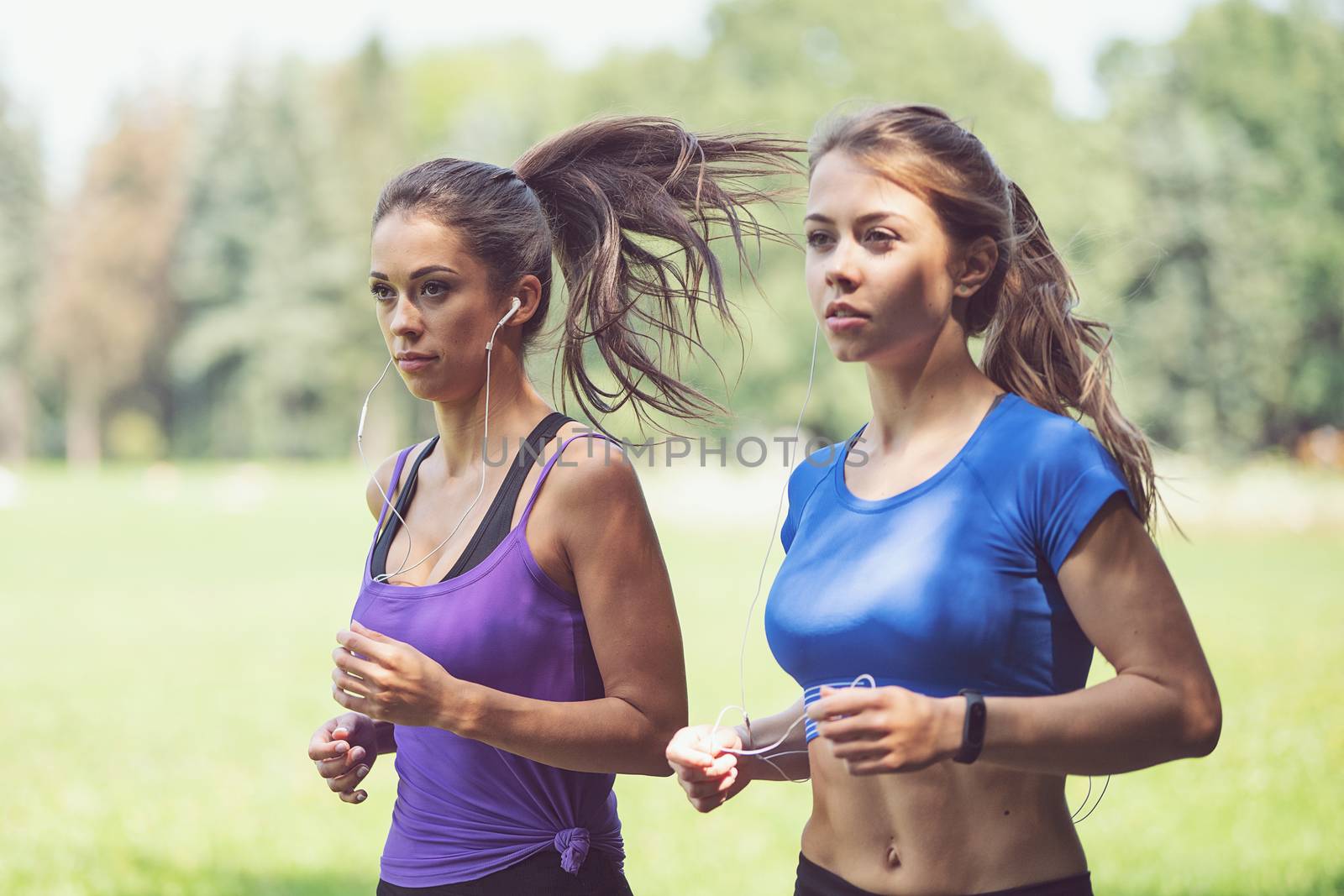 Two beautiful and attractive fitness girls are jogging in the park on a sunny morning (vintage effect)