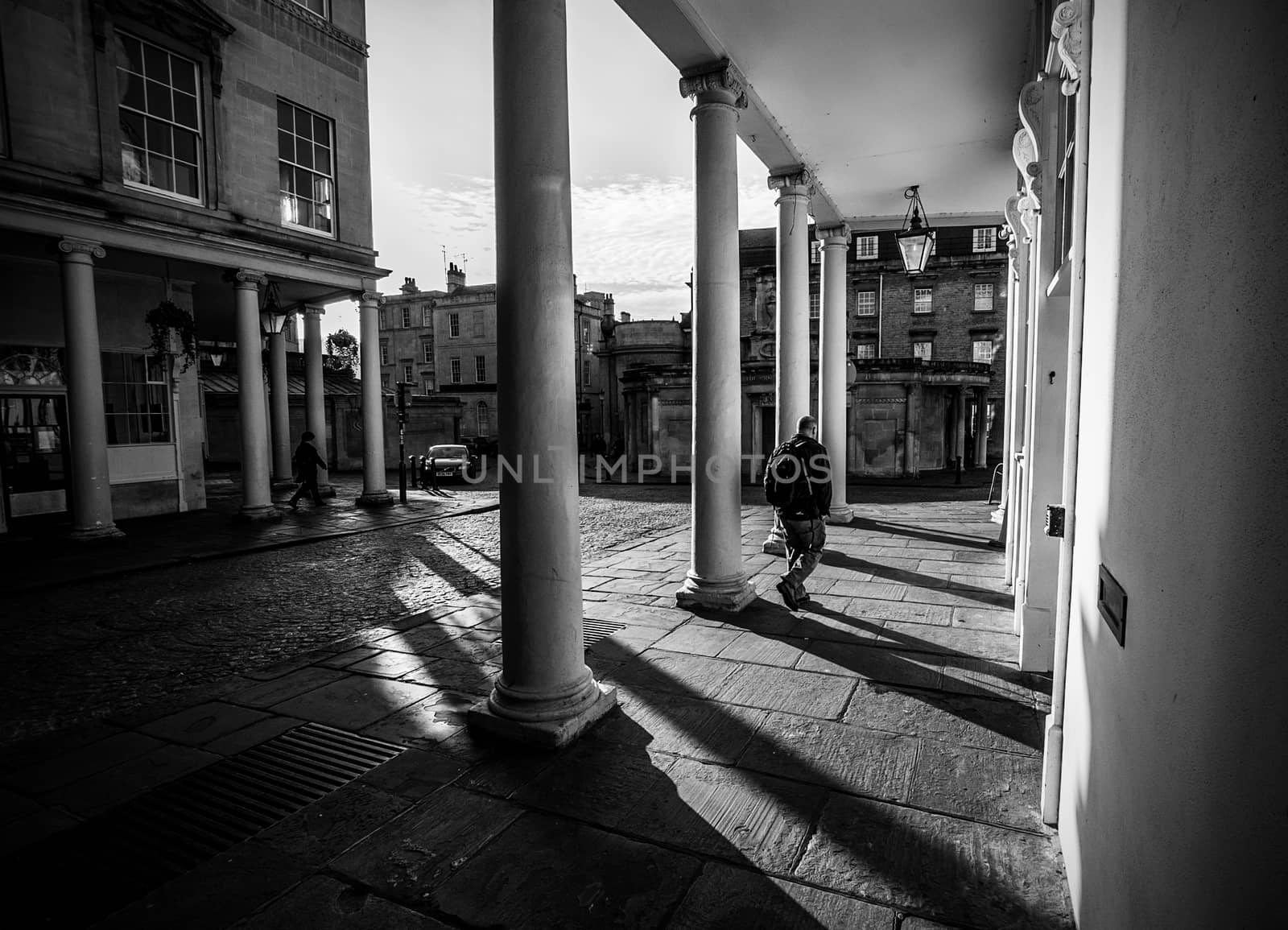 black and white shadows of man walking among pillars
