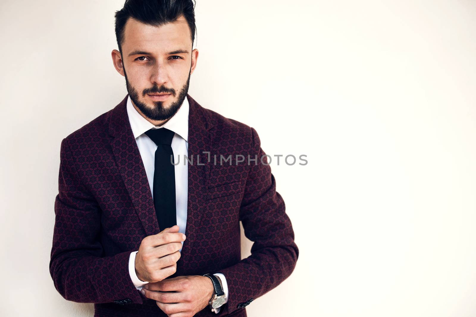 Young and fashionable man buttoning a cuff and posing on a white background ( copy space)