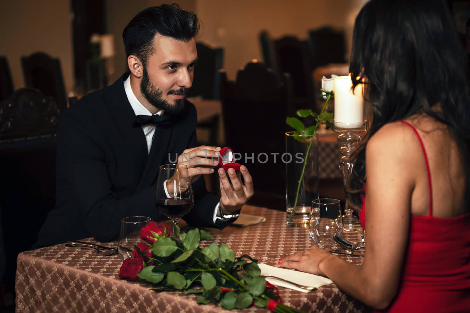 Man surprising woman with engagement ring at the restaurant during romantic dinner