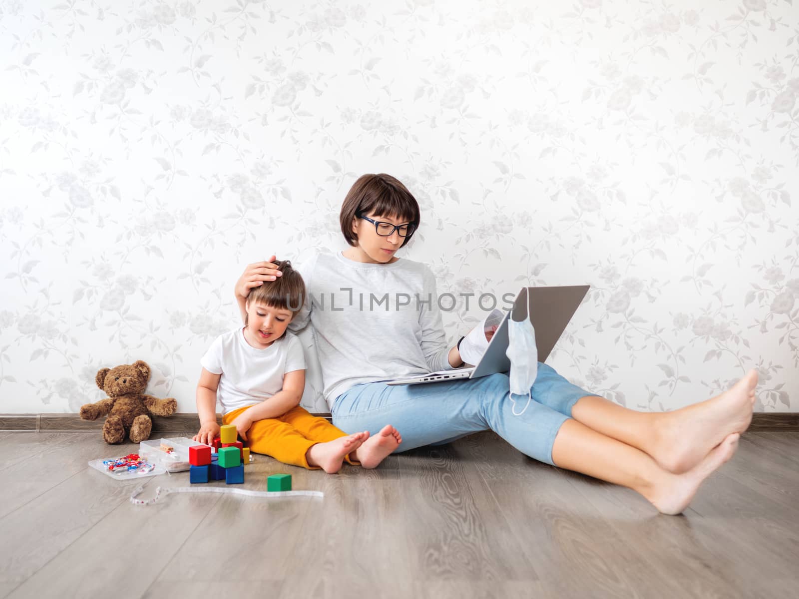 Mom and son at home. Mother works remotely with laptop, son sits by aksenovko