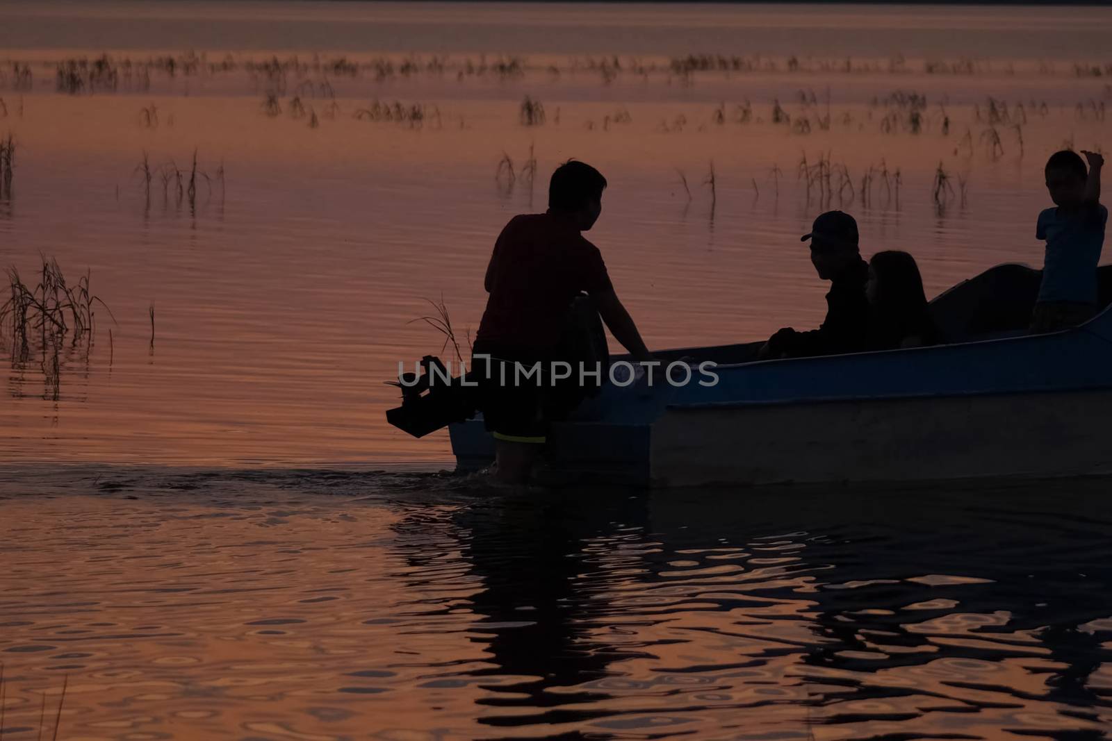 Silhouettes of fishermen on the river near boat. Pushing the boat. by DePo