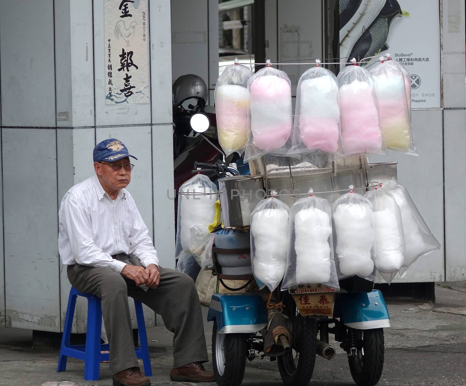 KAOHSIUNG, TAIWAN -- FEBRUARY 16, 2018: An elderly man sells home-made cotton candy from three wheel scooter.

