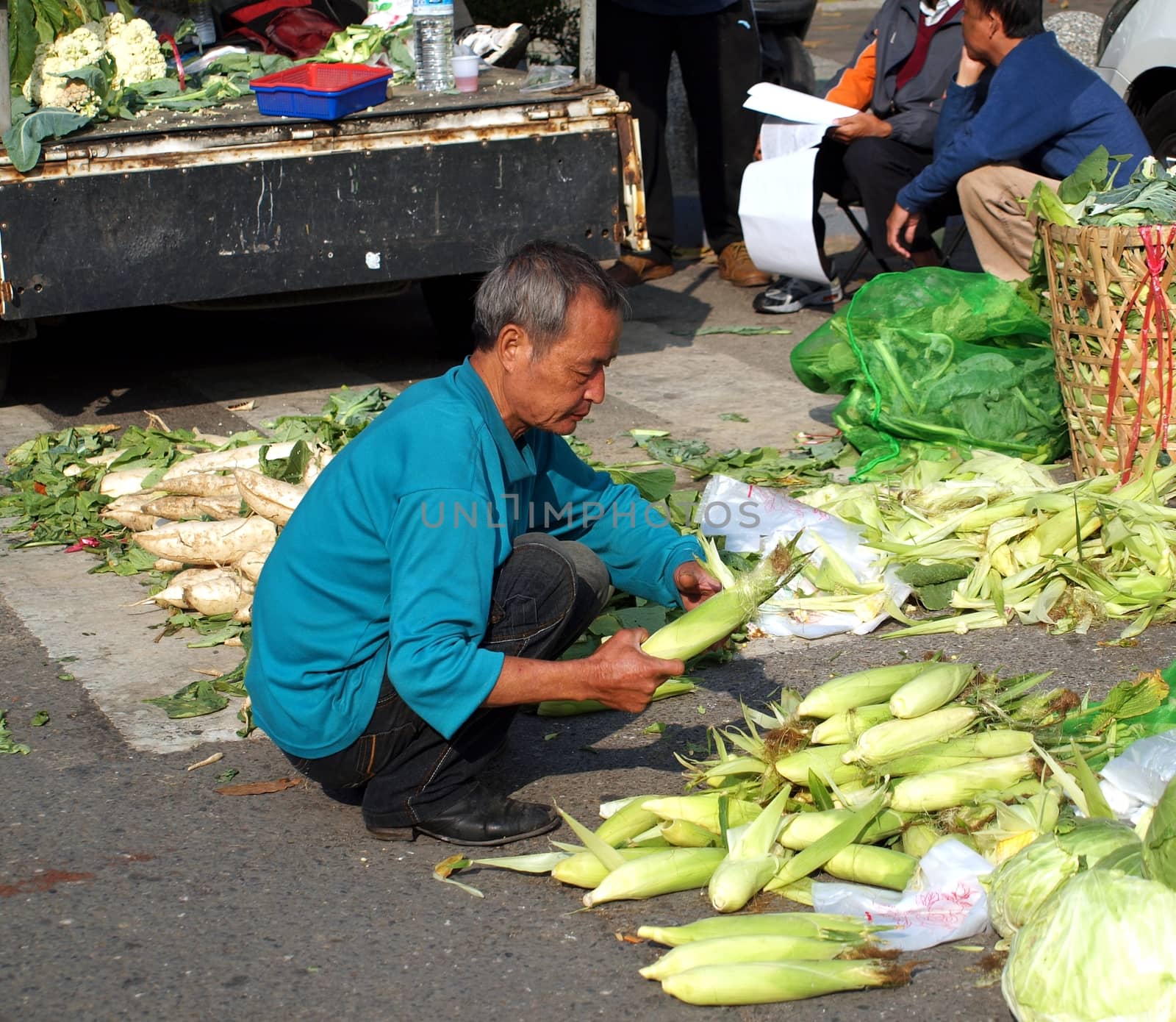 KAOHSIUNG, TAIWAN - FEBRUARY 9: An unidentified shopper removes the husks from corn at an outdoor market on February 9, 2013 in Kaohsiung.