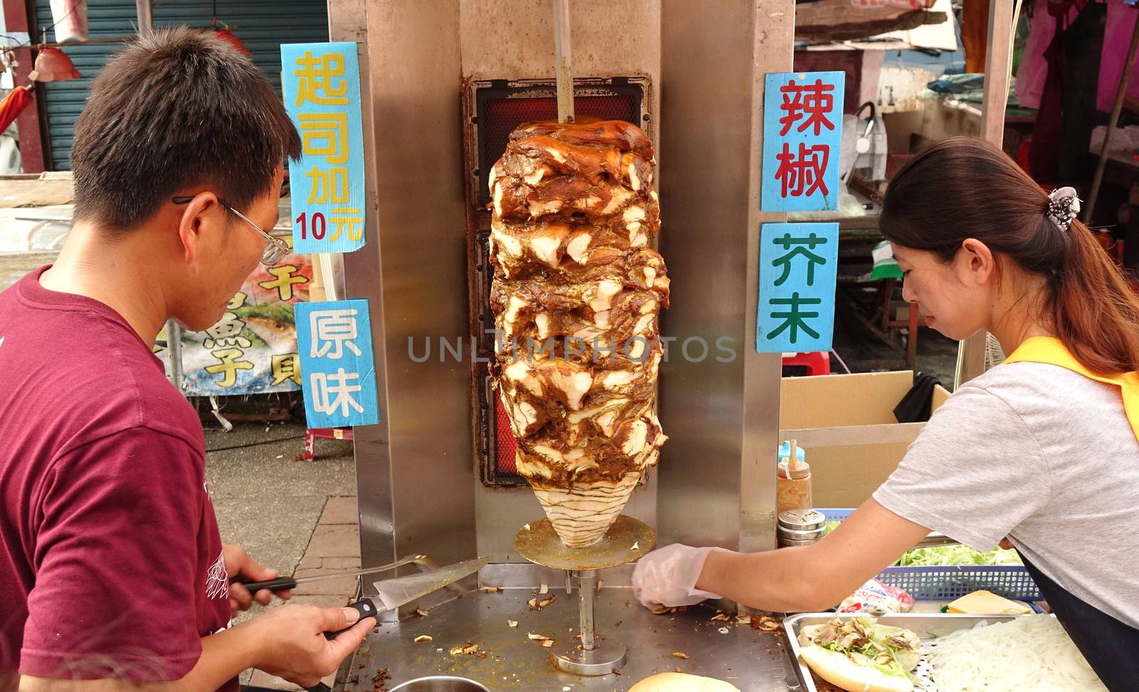 KAOHSIUNG, TAIWAN -- OCTOBER 15, 2016: Two outdoor vendors prepare Shawarma in bread buns at a popular outdoor market.