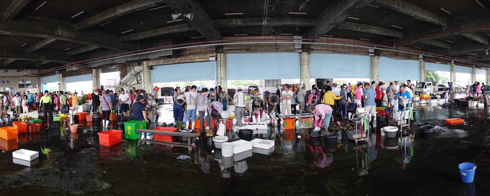 KAOHSIUNG, TAIWAN -- APRIL 24, 2016: Shoppers at the Sinda Port fish market check out the fish and seafood that is on sale in baskets and crates.