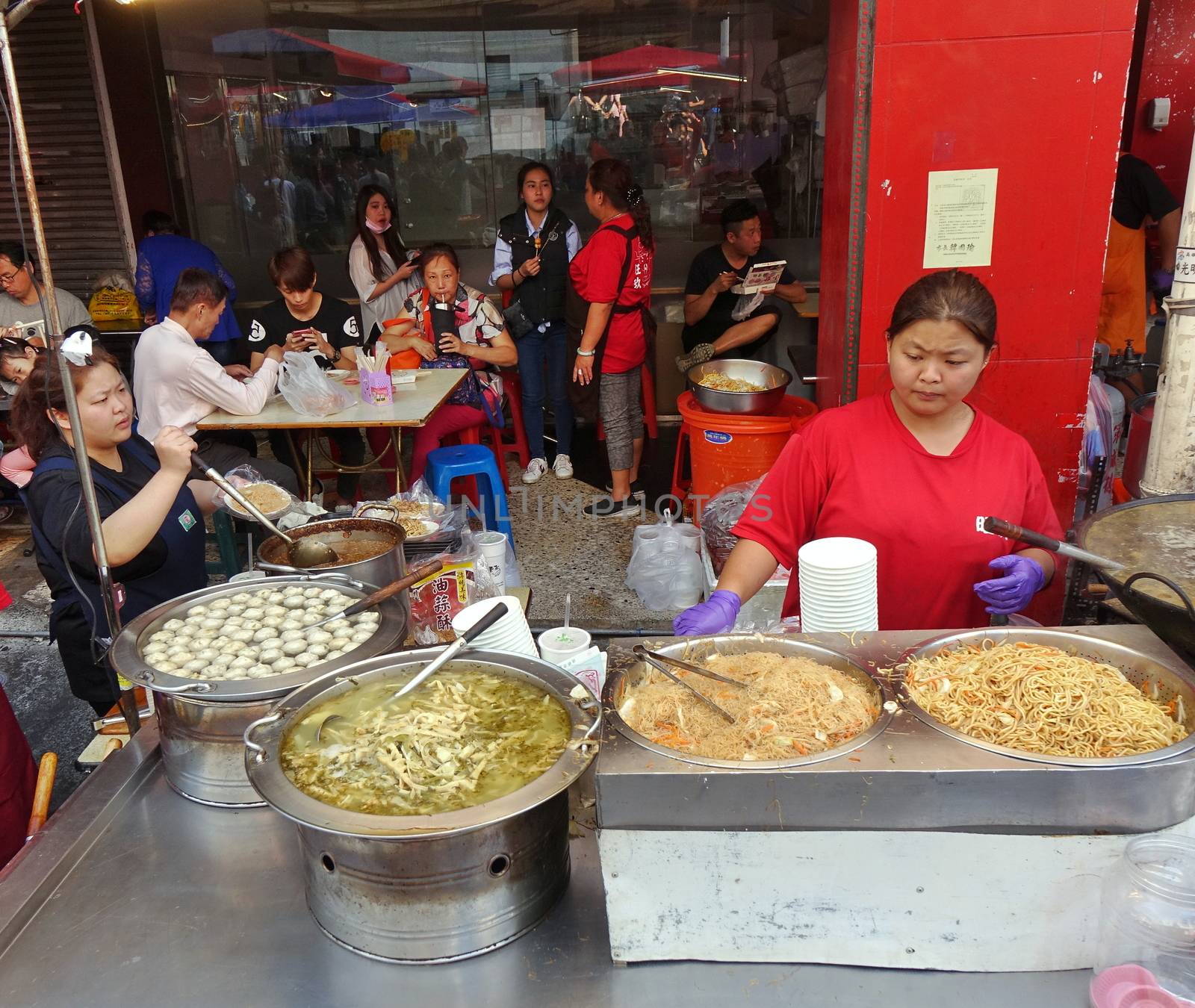 KAOHSIUNG, TAIWAN -- FEBRUARY 6, 2019: A street vendor cooks fried noodles, fish balls and pickled bamboo soup.

