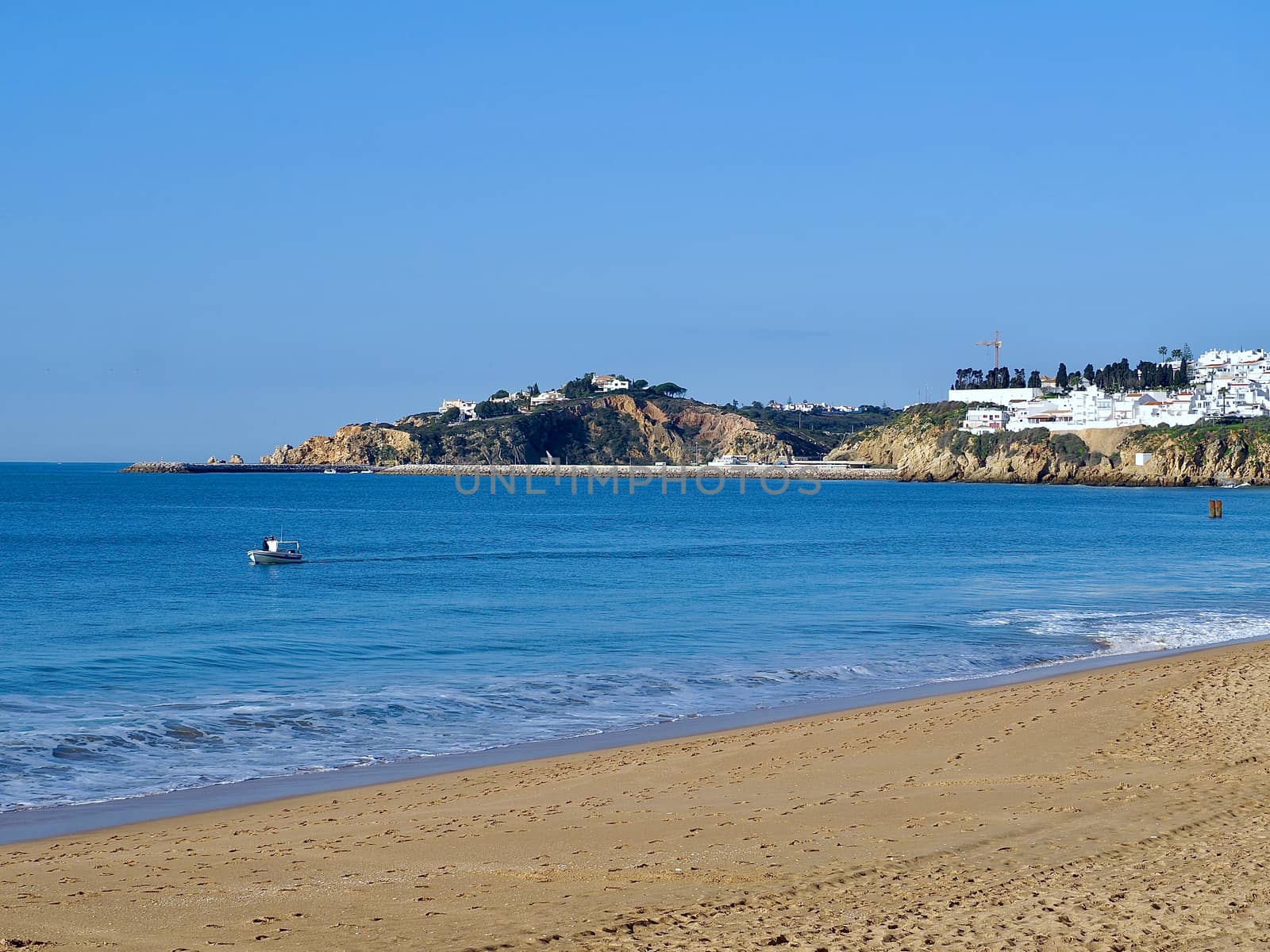 Coast of Albufeira with a fisher boat on blue sea