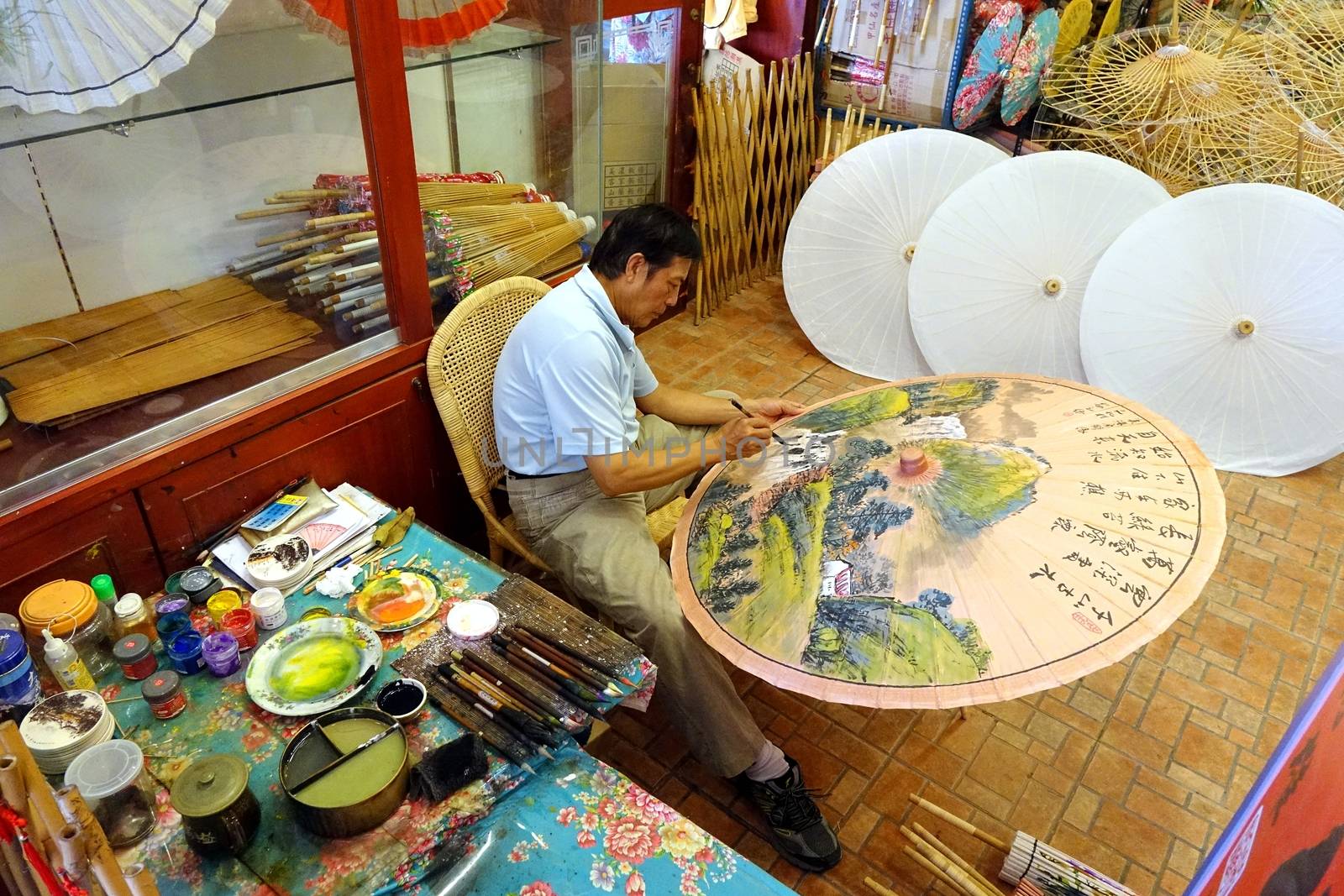 KAOHSIUNG, TAIWAN -- JULY 24, 2016: A male artist paints oil-paper umbrellas, which is a traditional art and craft product by the Chinese Hakka people.