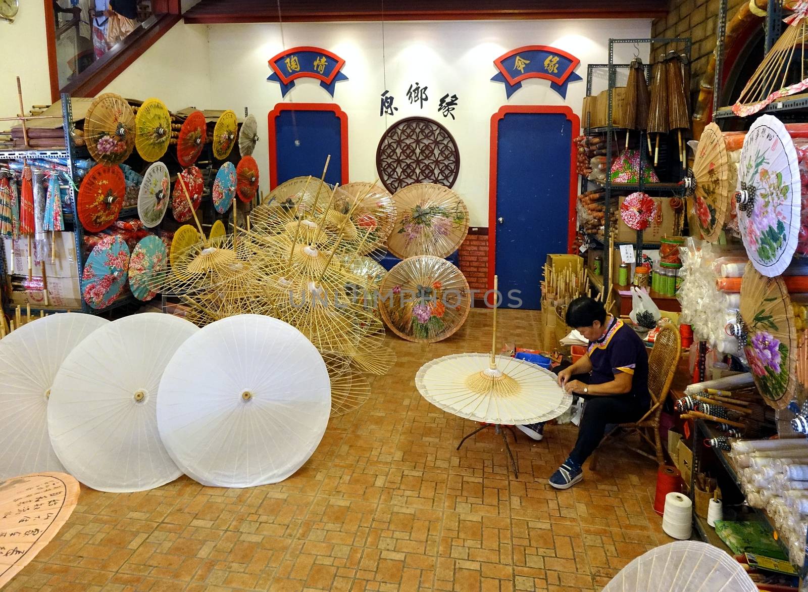 KAOHSIUNG, TAIWAN -- JULY 24, 2016: A female craftsperson makes oil-paper umbrellas, which is a traditional art and craft product by the Chinese Hakka people.