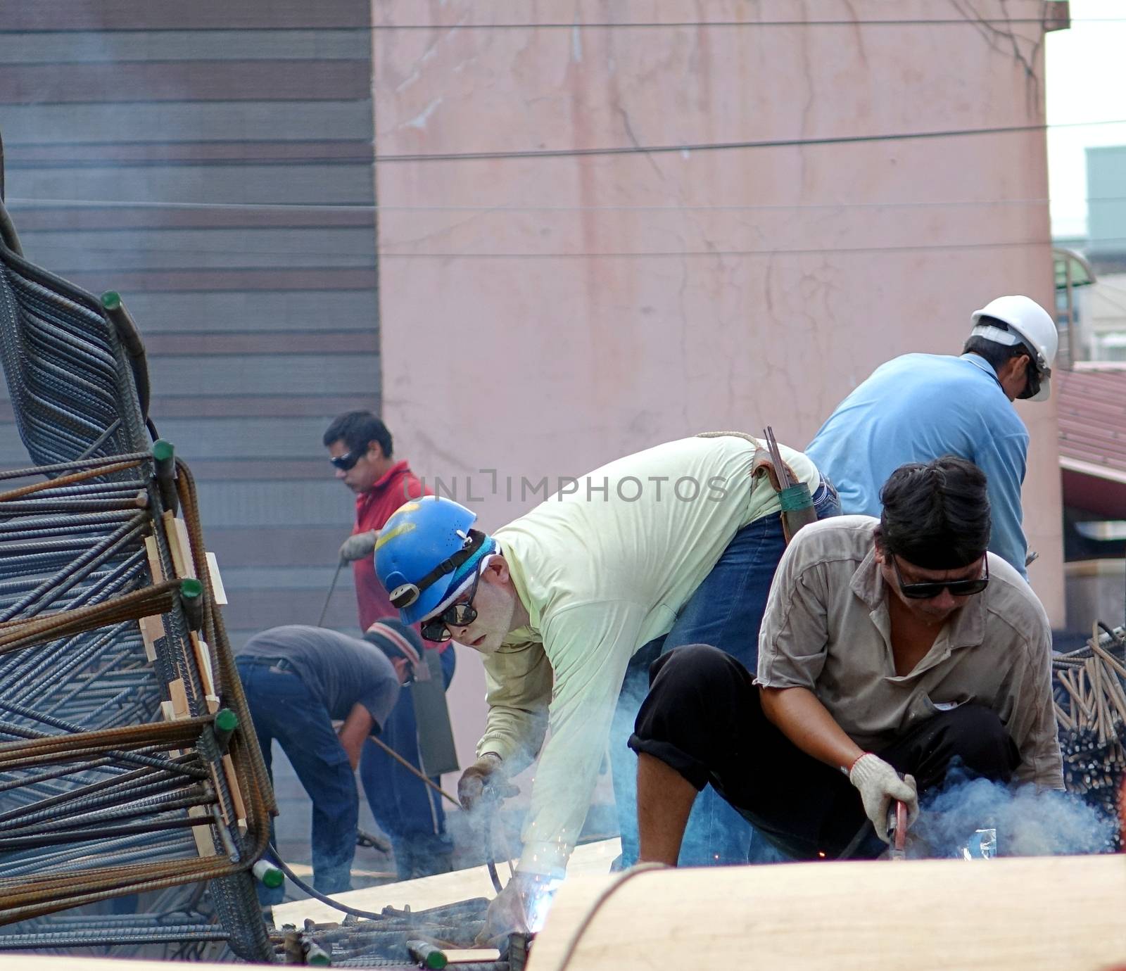 KAOHSIUNG, TAIWAN -- SEPTEMBER 20, 2015: Construction workers with welding equipment assemble a metal structure used to reinforce the building foundation.
