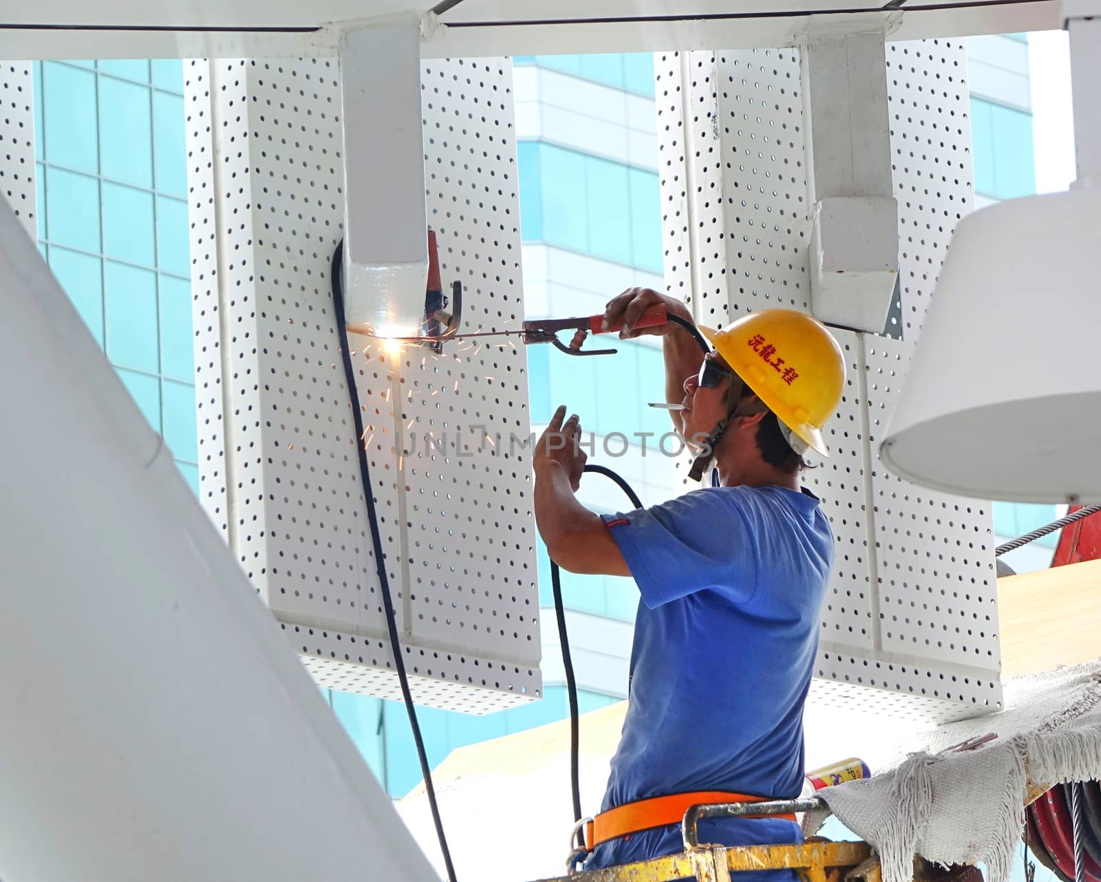 KAOHSIUNG, TAIWAN -- AUGUST 7, 2017: A worker with a helmet performs welding operations without adequate safety equipment.