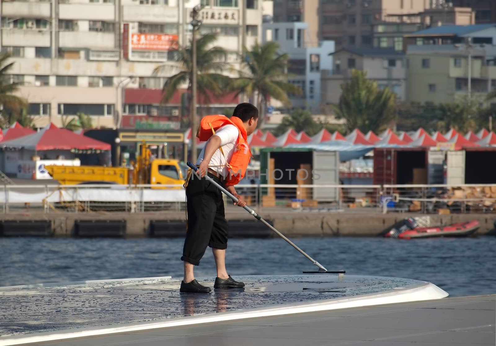 KAOHSIUNG, TAIWAN - FEBRUARY 22: An unidentified crew member washes the solar panelled roof of a sightseeing boat on the Love River on February 22, 2013 in Kaohsiung.