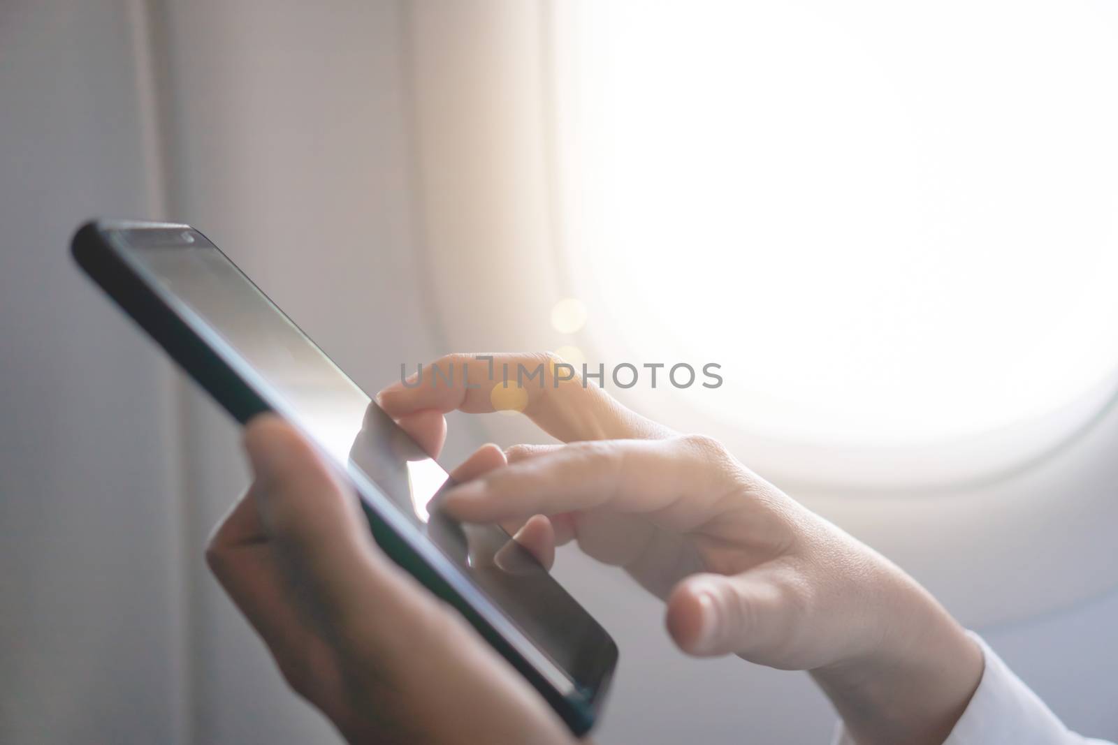 Woman hand use smartphone in airplane in offline mode during flight work and travel concept.