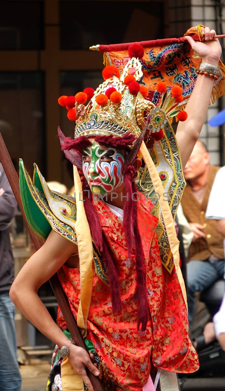 KAOHSIUNG, TAIWAN -- MARCH 16, 2014: A young man with painted facial mask and dressed up as an ancient warrior dances at a local temple ceremony.