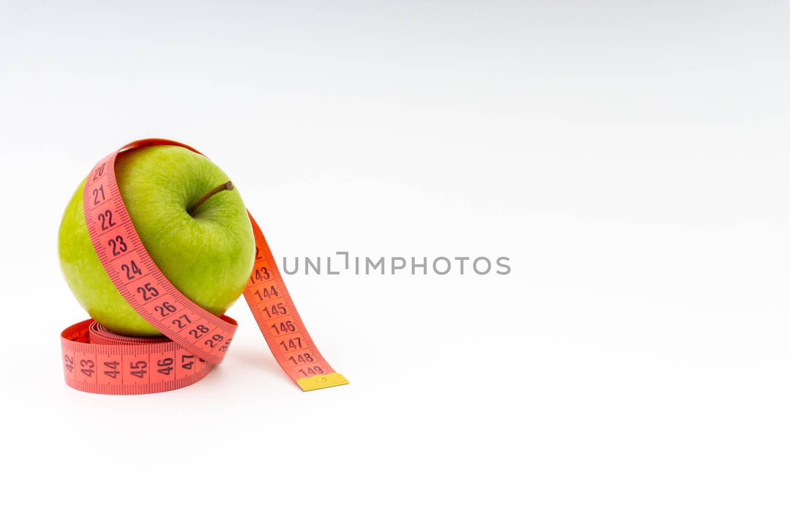 Green apple with red measuring tape. Health care and body fitness concept