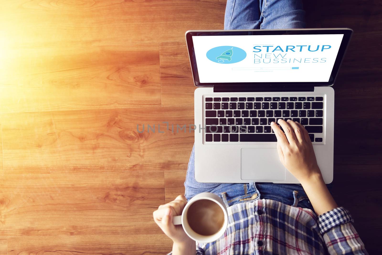 top view of people working on notebook laptop computer from home on wooden floor with startup business and rocket logo on screen, start up ideas business development