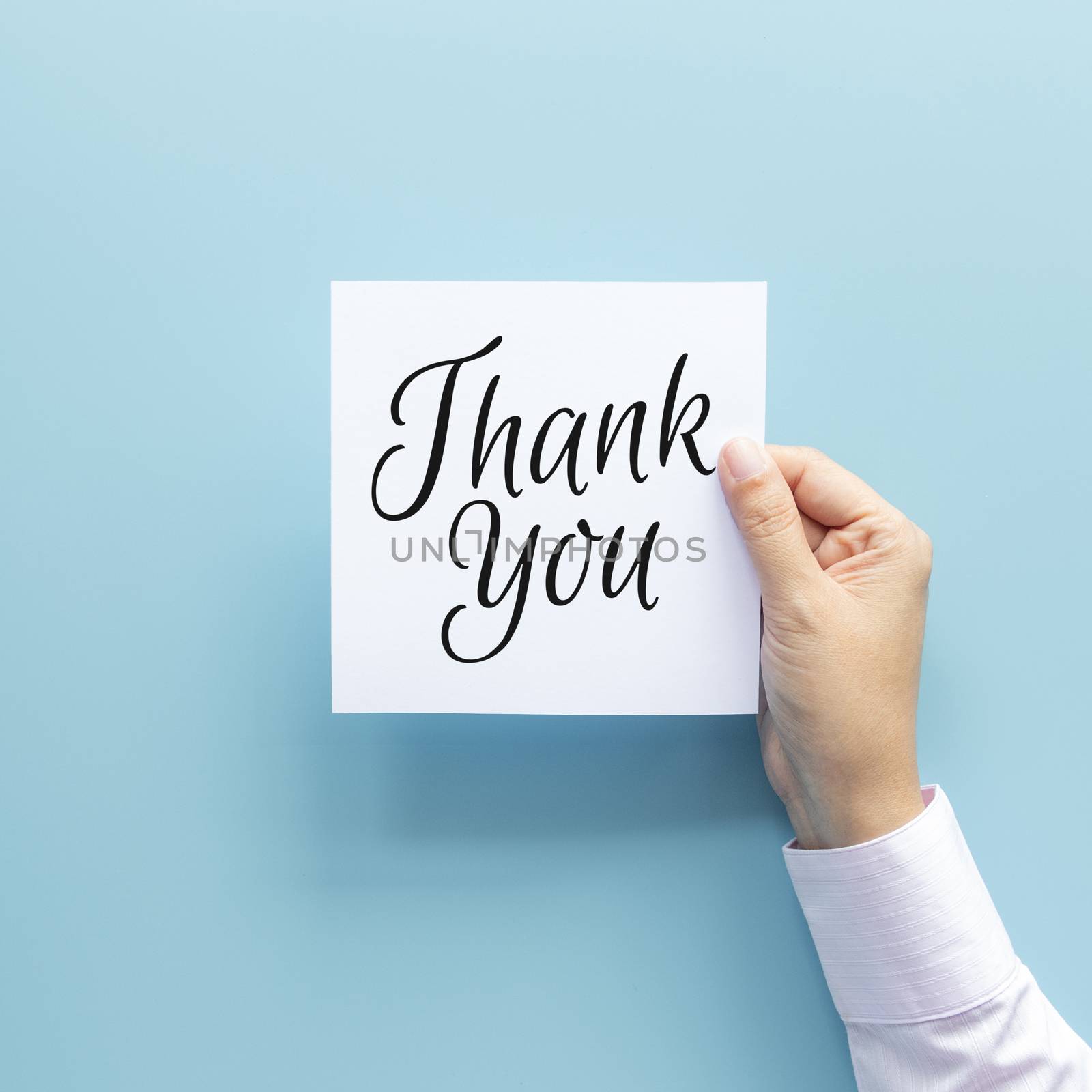 woman hand holding card with the word thank you isolated on blue background, studio shot by asiandelight