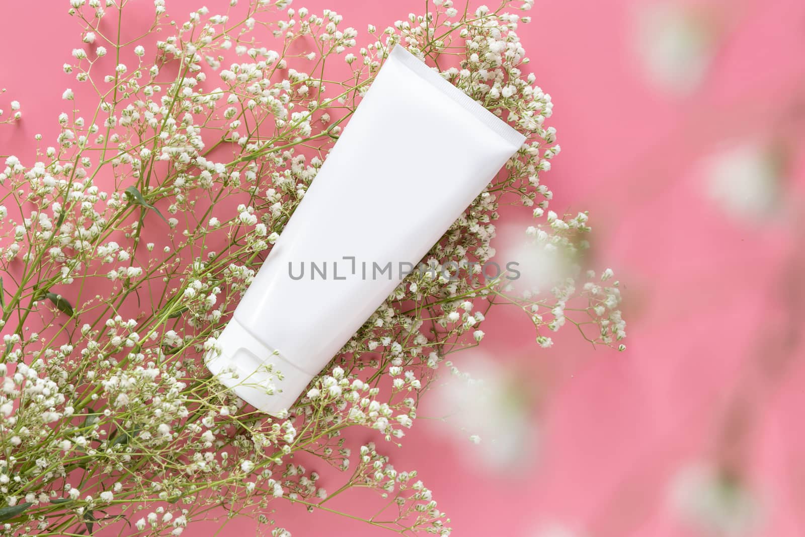 cosmetic nature organic skincare concept. white cosmetic tube container with blank label for branding packaging  mock up, decorate with white flower on pink background with copy space by asiandelight
