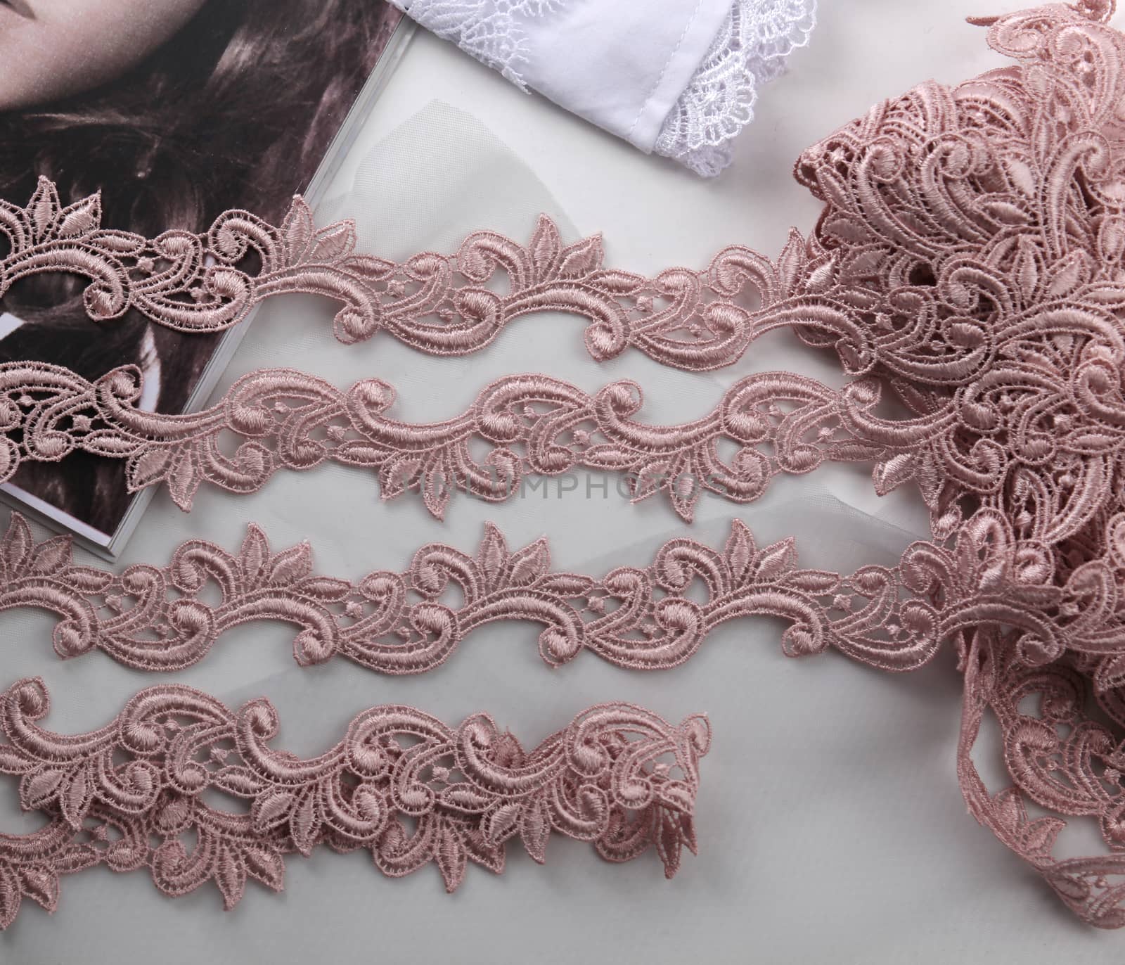 Tapes of pink gentle guipure, beauty lace fabric on light background. Elastic material. Using for Atelier and needlework store.