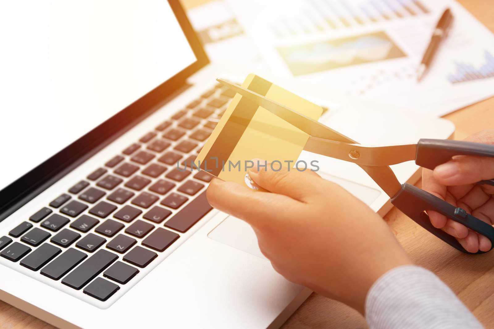 woman use scissors to cut credit cards in hand in front of computer laptop by asiandelight