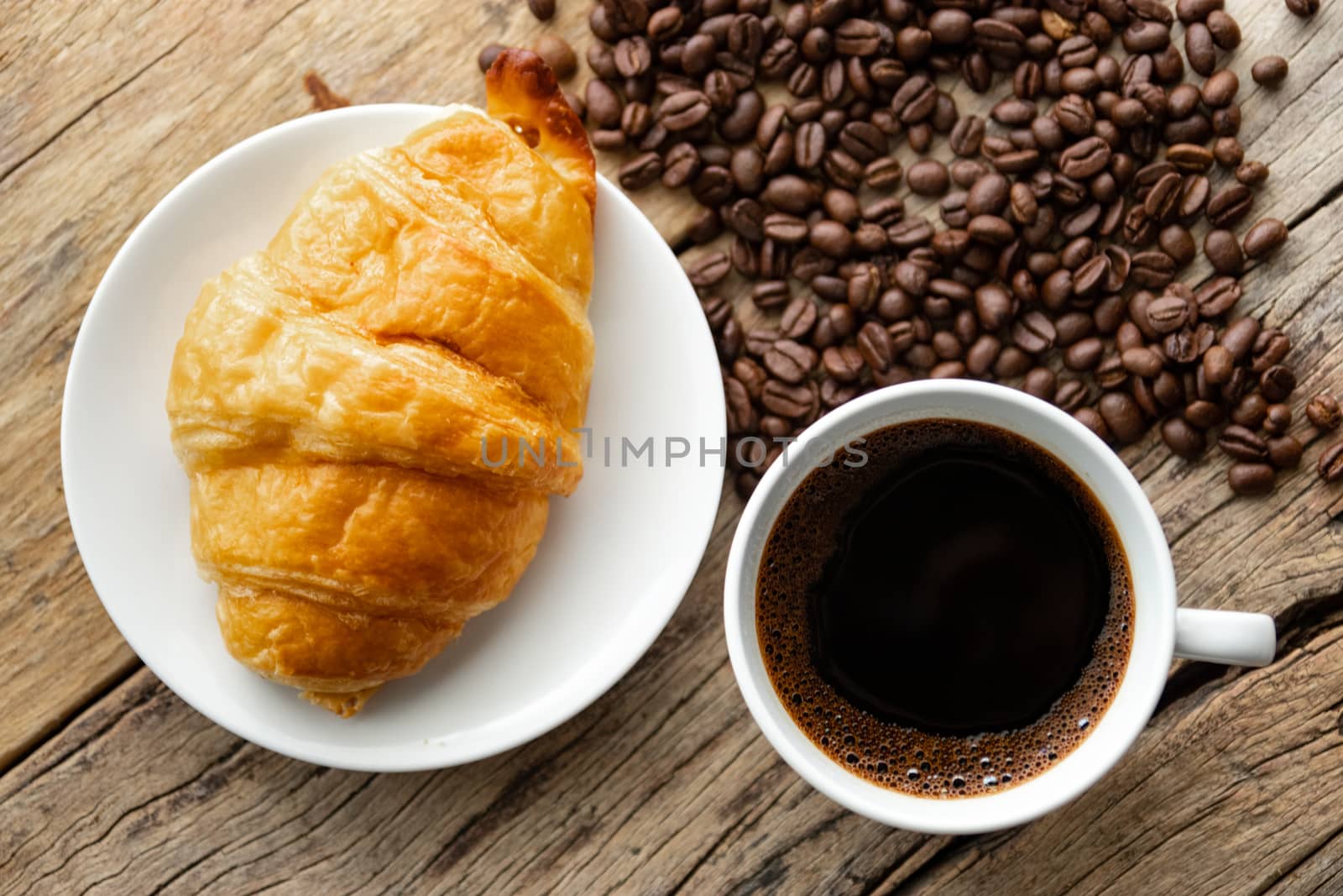 continental breakfast with fresh croissant and hot coffee on wooden background, decoration with coffee bean by asiandelight