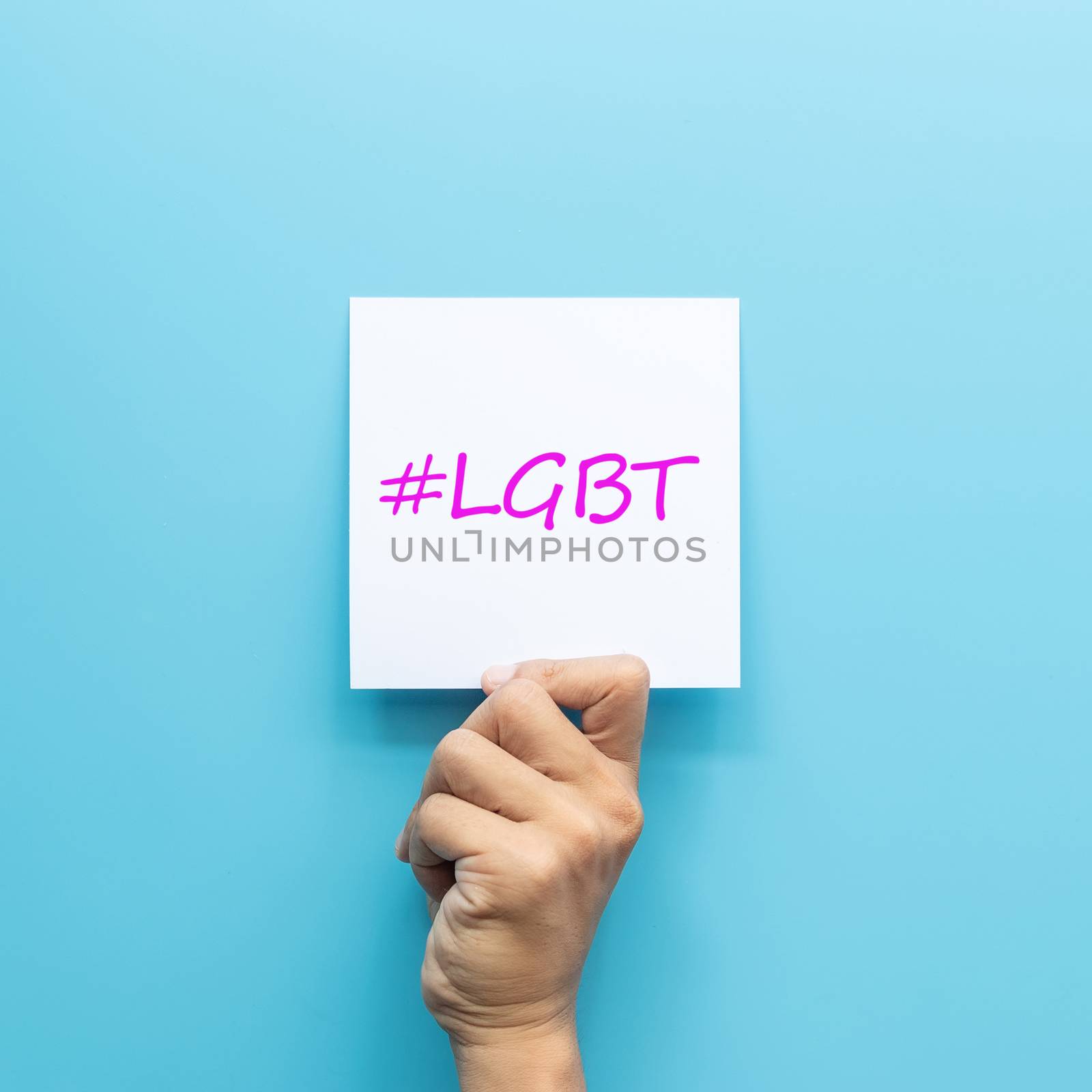 hashtag #LGBT on white paper in hand isolated on blue background by asiandelight