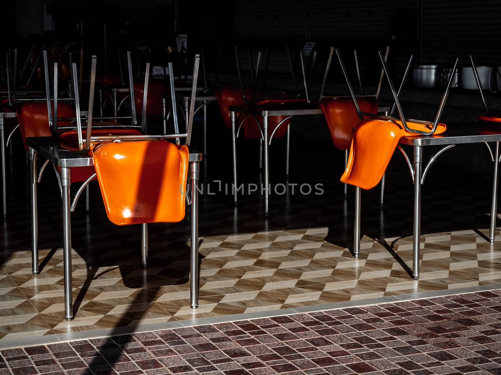 Upside down chairs, orange colour on tables in restaurant due to city lockdown during Coronavirus or Covid-19 pandemic to stop infection spreading crisis.