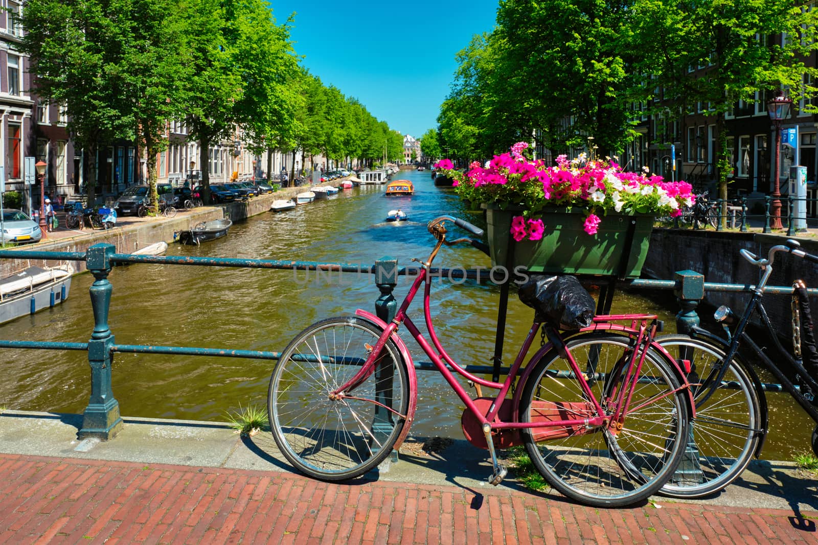 Typical Amsterdam view - Amsterdam canal with boats and parked bicycles on a bridge with flowers. Amsterdam, Netherlands