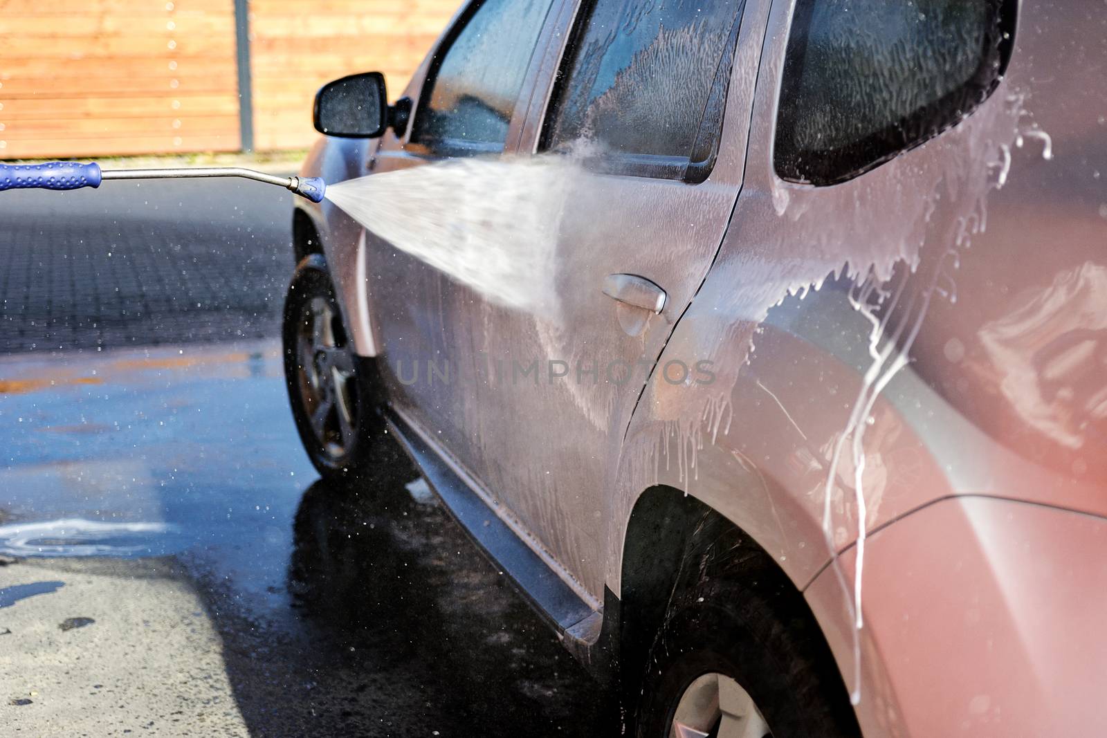 Washing car under high pressure with water and shampoo in close-up