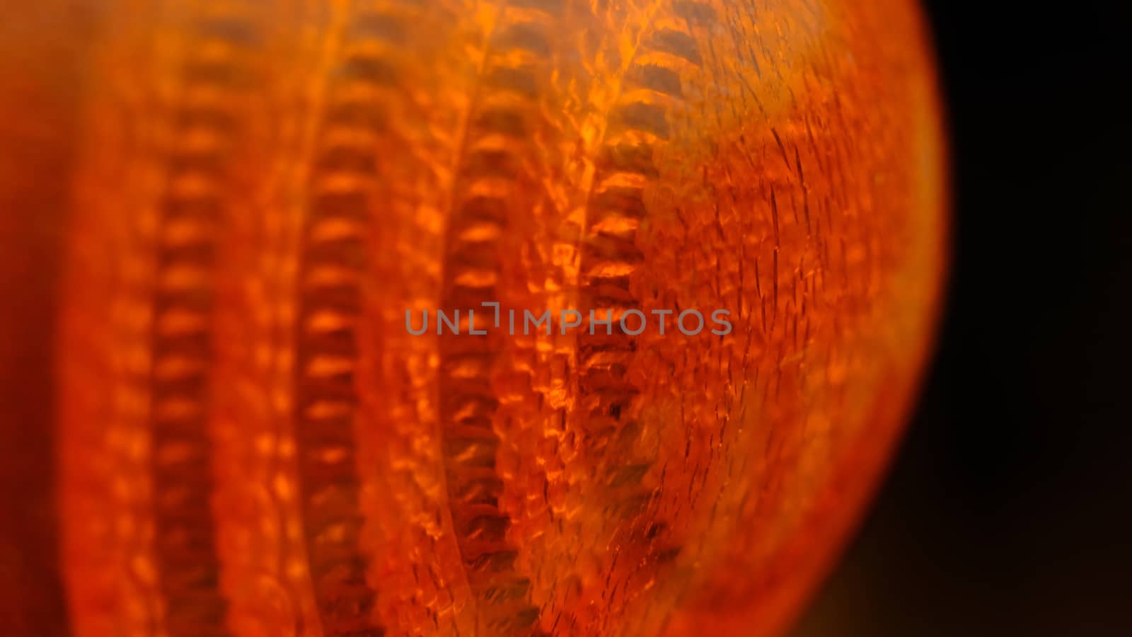 Closeup macro photography of orange glass lamp texture. Illuminated background by Macrostud