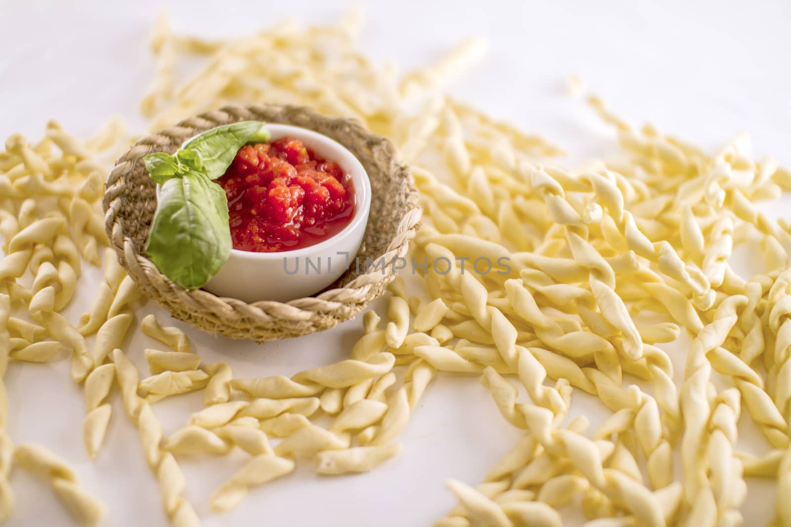 Close up still life of italian handmade pasta fusilli al ferretto with tomato puree and basil on white background