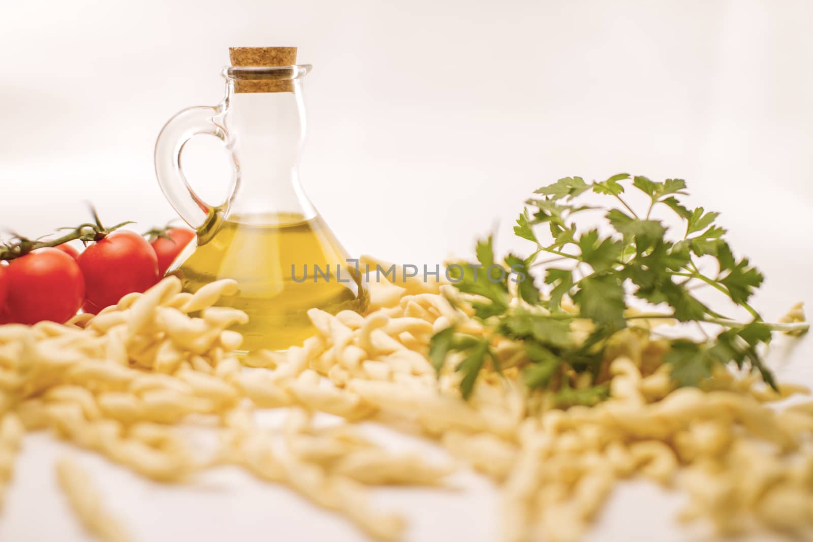 Close up still life of italian handmade pasta fusilli al ferretto with tomatoes, parsley and extra virgin olive oil on white background