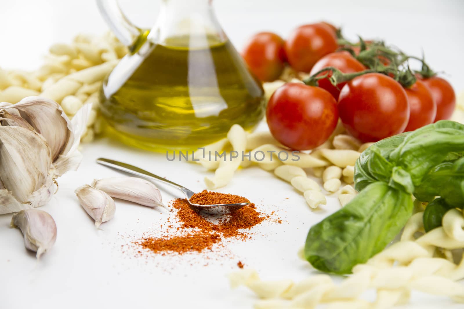 Close-up of italian typical pasta recipe: handmade durum wheat flour pasta, tomatoes, garlic, extra virgin olive oil, ground chili, parsley and basil on white background
